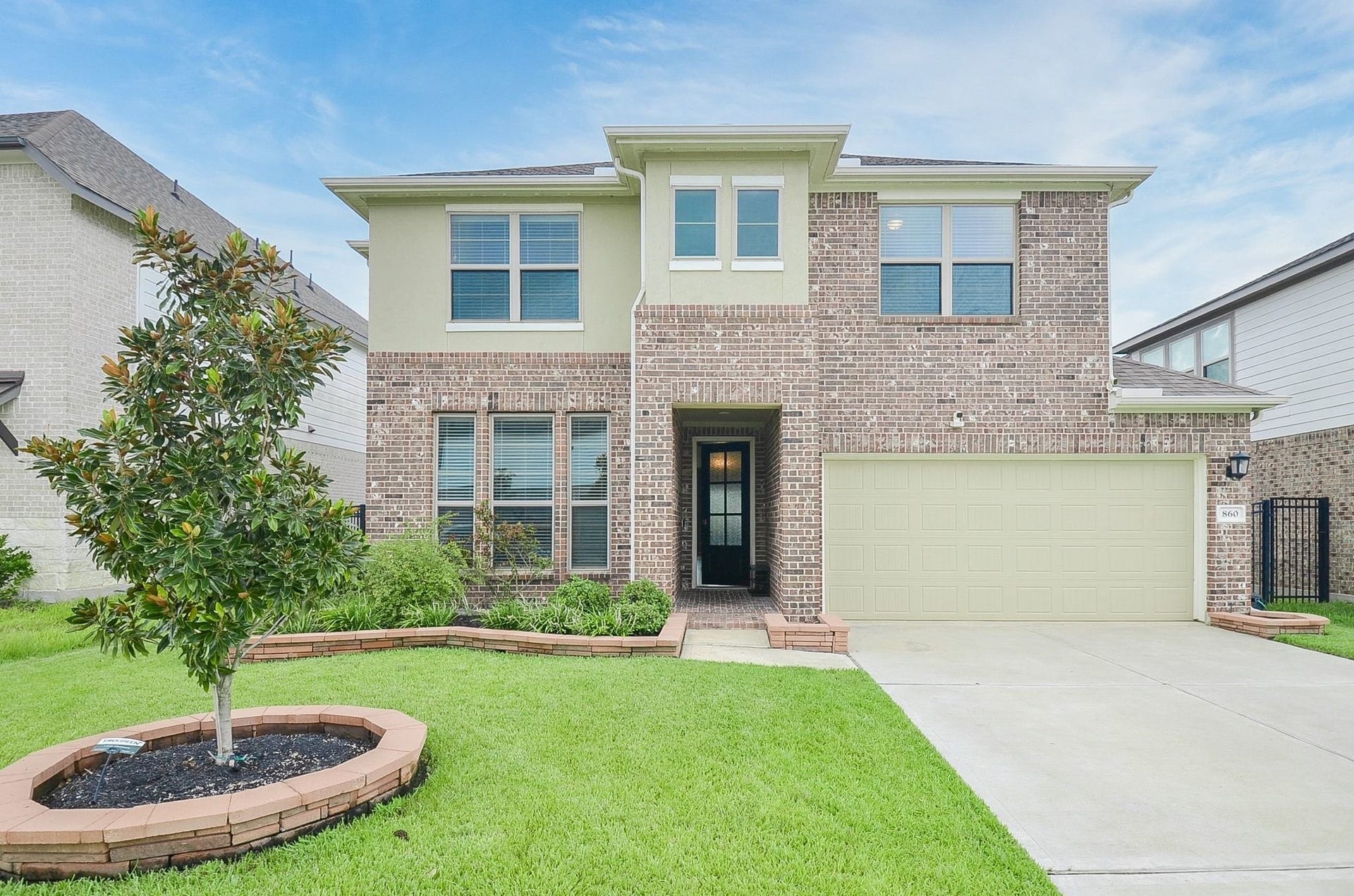 860 Marisol Bay Drive, Katy, TX 77493 Two-story brick home with modern windows, a well-maintained front yard, and a spacious two-car garage.