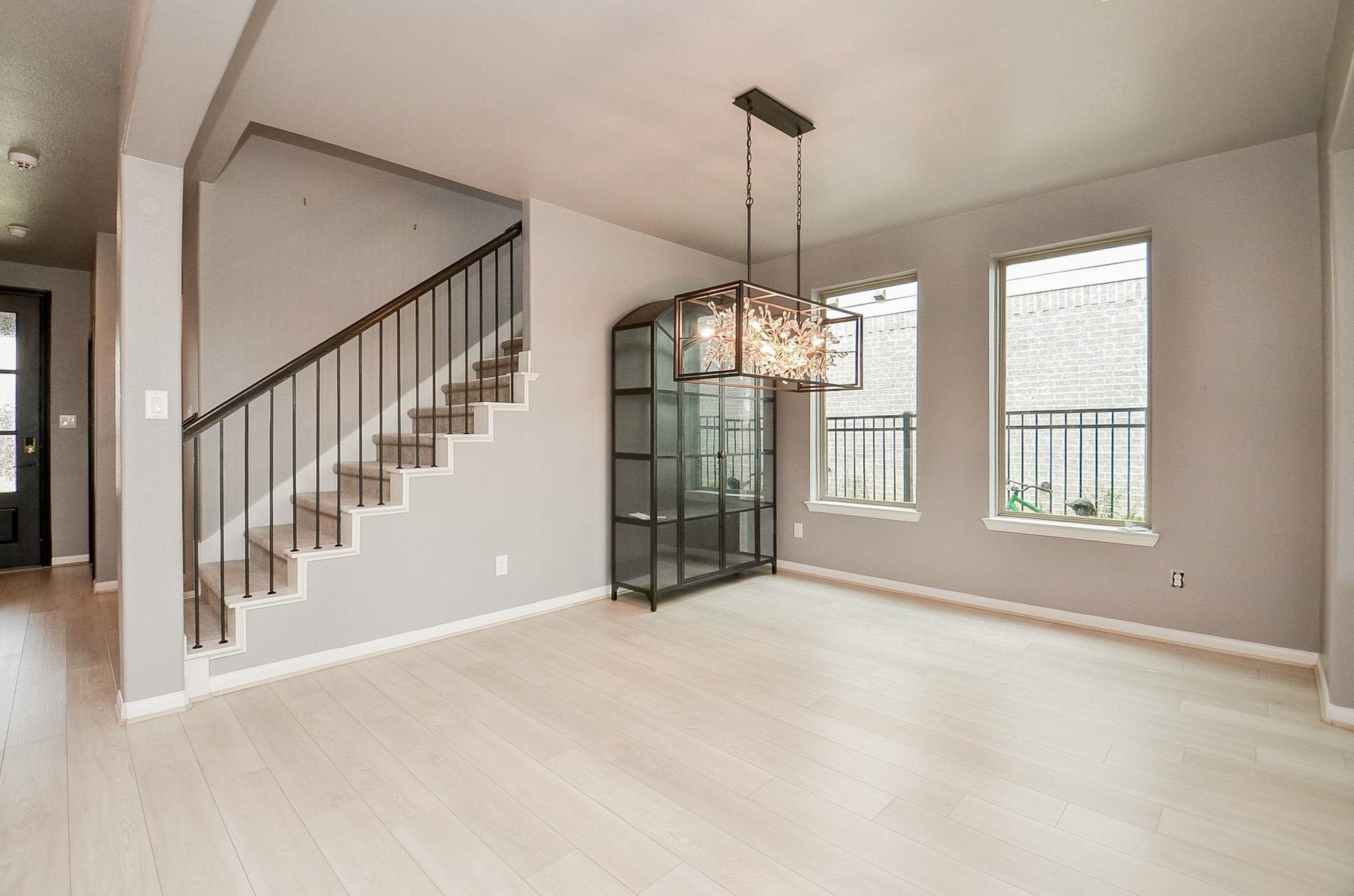 860 Marisol Bay Drive, Katy, TX 77493 This open dining area is accented with a striking chandelier and large windows that invite natural light, alongside a stylish staircase with sleek railing. (Curio Cabinet to be removed)