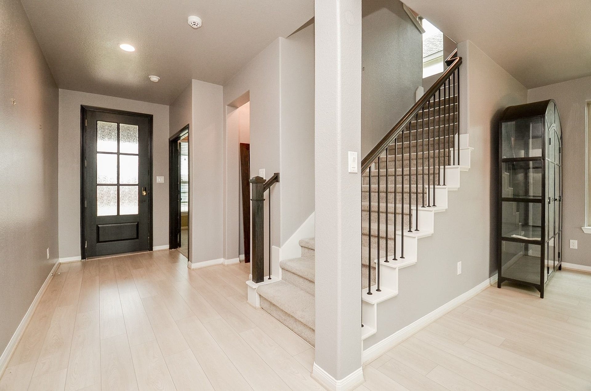 860 Marisol Bay Drive, Katy, TX 77493 Bright and inviting entryway featuring wood look laminate flooring, a modern staircase with iron railings, and a stylish black front door.