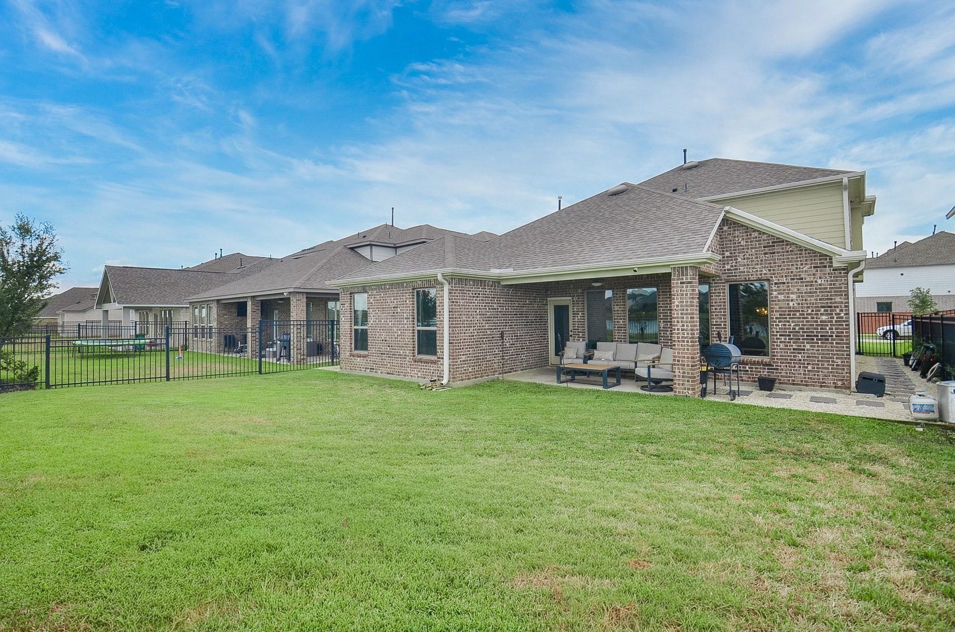 860 Marisol Bay Drive, Katy, TX 77493 Spacious backyard with a charming brick exterior, covered patio, and well-maintained lawn perfect for outdoor relaxation and entertaining.