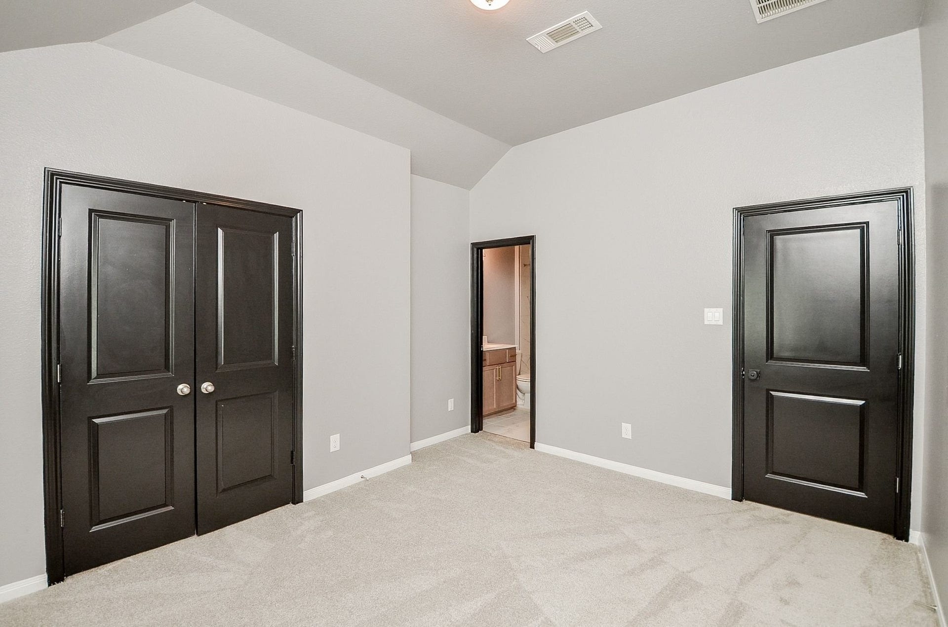860 Marisol Bay Drive, Katy, TX 77493 One of the two upstairs bedroom with clean lines, featuring fresh gray walls, plush carpet, and elegant black doors, leading to an en-suite bathroom for added convenience.