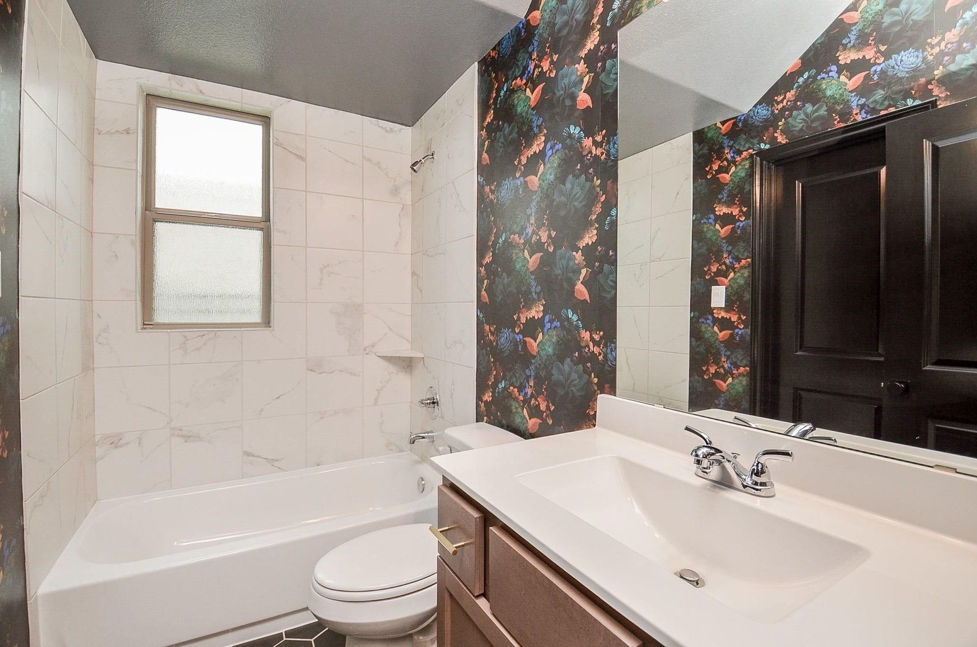 860 Marisol Bay Drive, Katy, TX 77493 Stylish first floor bathroom featuring a sleek white vanity and bathtub, complemented by elegant marble tile and vibrant floral wallpaper for a touch of modern flair.
