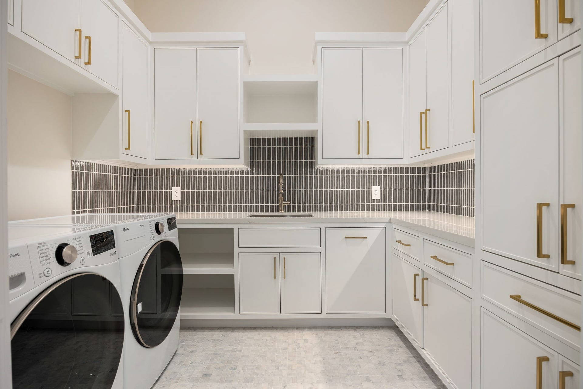 14106 Heatherfield Drive, Houston, TX 77079 This beautifully appointed laundry room blends efficiency with elevated design, featuring extensive custom cabinetry, generous counter space, and a clean, cohesive layout. The neutral tones are complemented by warm hardware and subtle texture throughout. The highlight of this room is the abundant built-in storage and folding space, offering exceptional organization while maintaining a bright, polished environment that makes daily tasks feel seamless and refined.