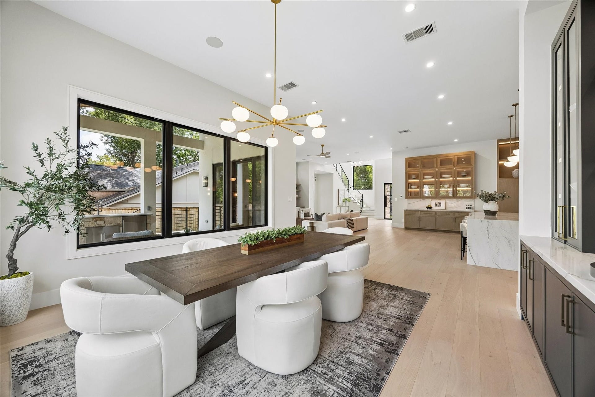 14106 Heatherfield Drive, Houston, TX 77079 An open-concept layout brings effortless flow to the heart of the home. The dining area transitions seamlessly into expansive living and kitchen spaces, unified by wide-plank wood flooring, crisp finishes and thoughtfully layered lighting. Oversized windows frame green outdoor views while custom cabinetry and built-ins add architectural character. The result is a bright, sophisticated setting equally suited to everyday living and elegant entertaining.