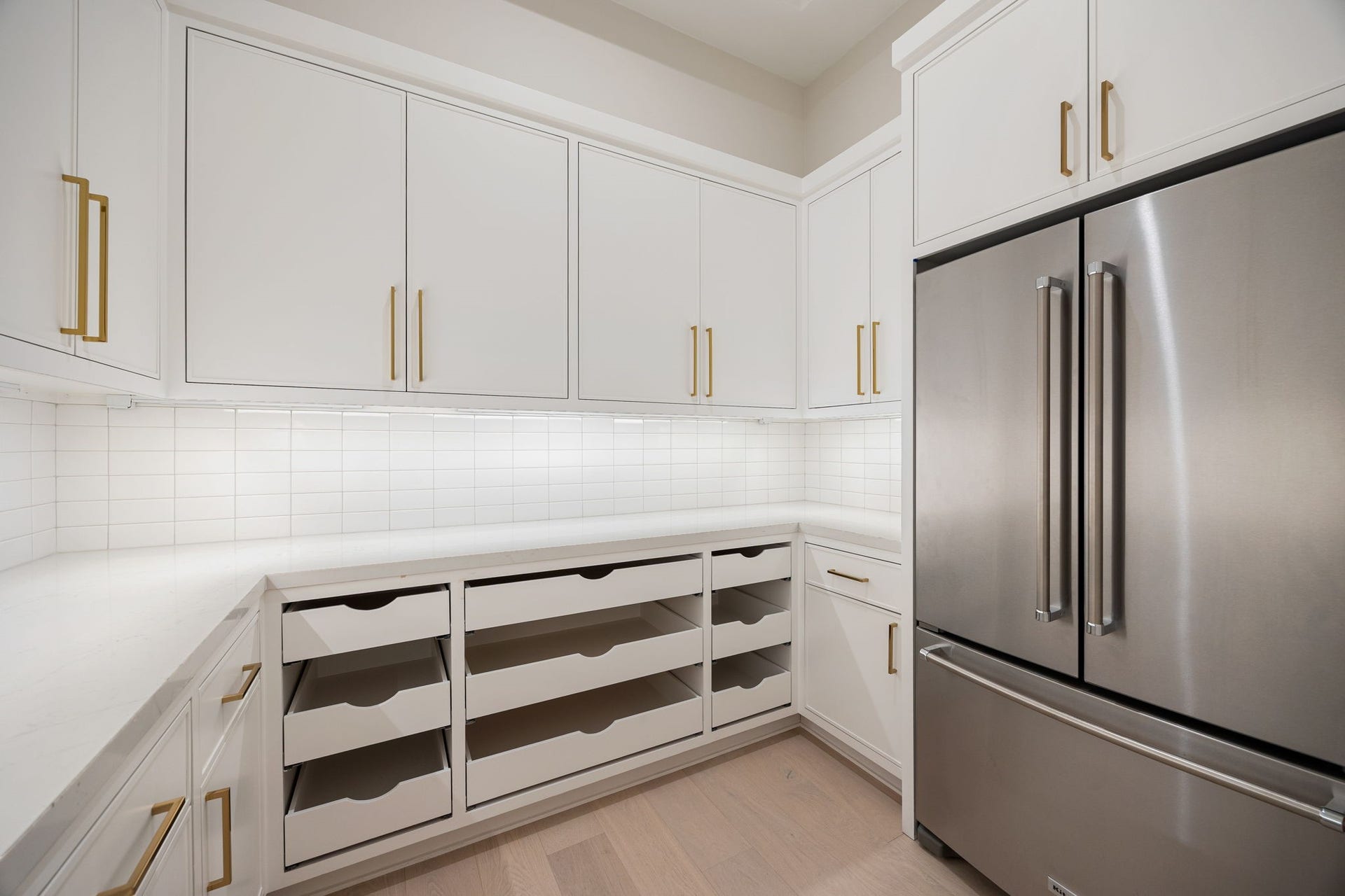 14106 Heatherfield Drive, Houston, TX 77079 A well-appointed secondary prep kitchen designed for organization and efficiency. Clean white cabinetry, ample storage, and thoughtful layout create a highly functional workspace. The standout feature is the custom storage system with pull-out drawers, offering exceptional organization while maintaining a clean, streamlined aesthetic.