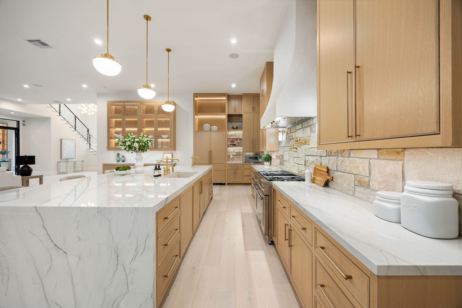 14106 Heatherfield Drive, Houston, TX 77079 A refined galley-style perspective showcases the length and functionality of this beautifully designed kitchen. Clean countertops, custom cabinetry, and warm finishes create a cohesive look throughout. The highlight is the extended island workspace, offering both prep and seating, while maintaining an open sightline to the surrounding living areas, enhancing flow and connectivity.