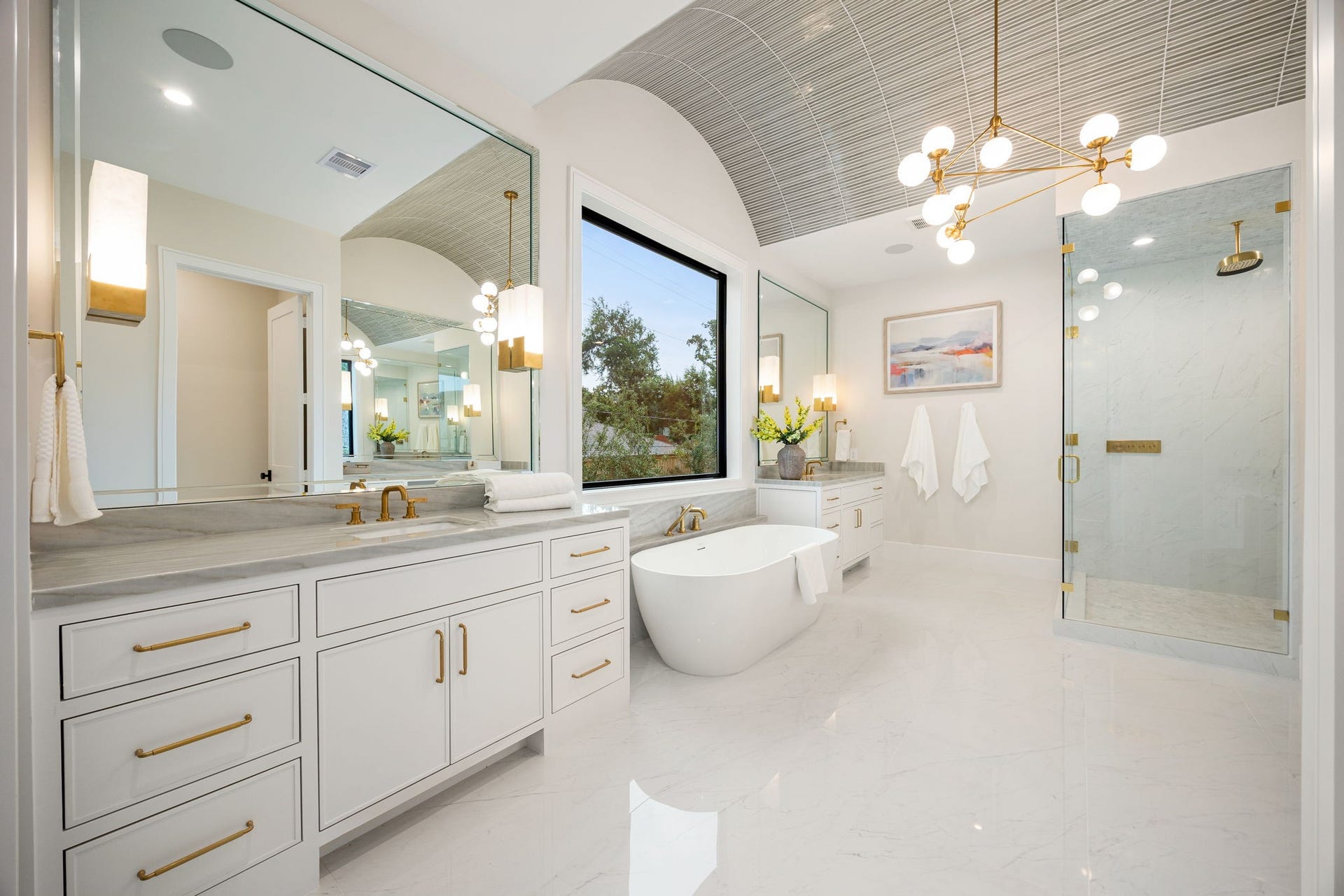 14106 Heatherfield Drive, Houston, TX 77079 A luxurious primary bathroom designed with a spa-like ambiance, featuring expansive dual vanities, elegant finishes, and abundant natural light. Clean lines and a neutral palette create a calming environment throughout. The highlight of this space is the freestanding soaking tub positioned beneath a large picture window, offering a serene focal point that elevates both relaxation and design.