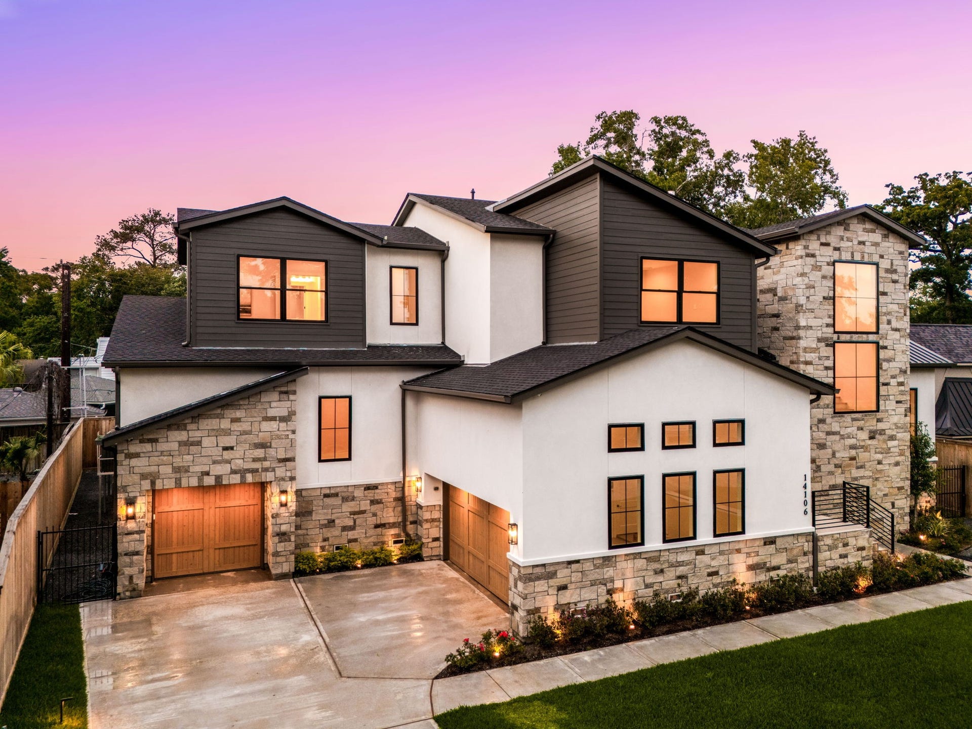 14106 Heatherfield Drive, Houston, TX 77079 This stunning exterior showcases modern architecture with a blend of stone and stucco, highlighted by clean lines and warm lighting that enhances curb appeal. Large windows glow beautifully at dusk. The highlight of this home is the striking architectural design with mixed materials and dramatic lighting, creating a memorable and sophisticated first impression.