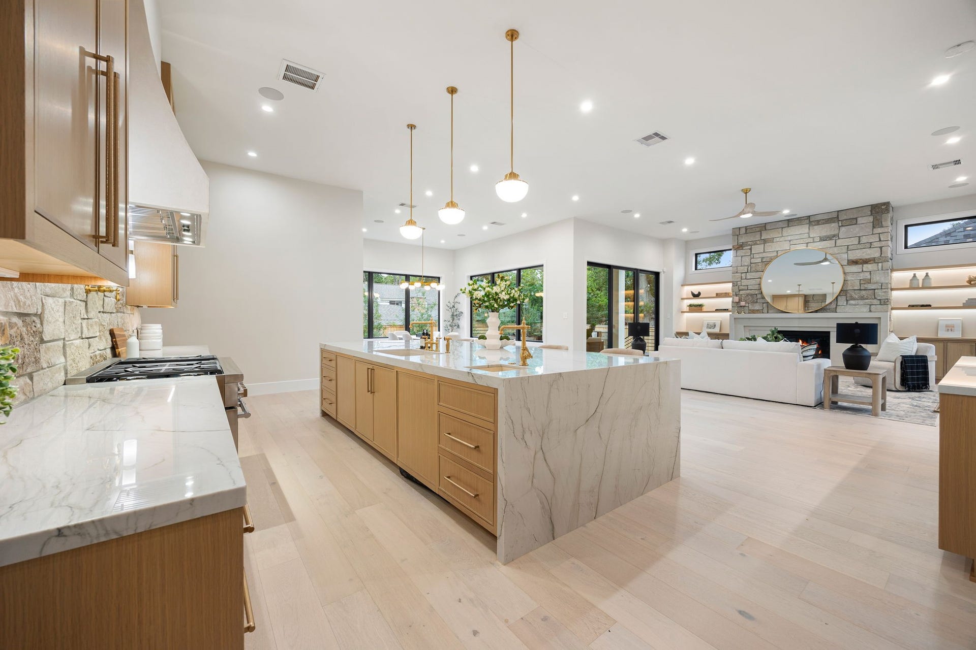 14106 Heatherfield Drive, Houston, TX 77079 This expansive view highlights the heart of the home, where the kitchen seamlessly opens to the living space. The oversized island provides generous prep and seating space, while natural light pours in through large windows. The standout feature is the effortless indoor-outdoor connection, creating a bright, airy atmosphere that enhances both everyday living and entertaining.