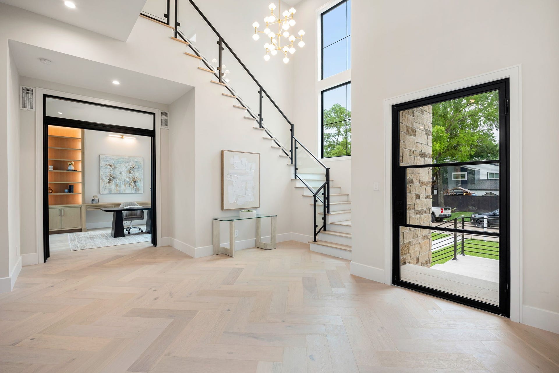 14106 Heatherfield Drive, Houston, TX 77079 A dramatic entry sets the tone with soaring ceilings, wide-plank flooring, and a sculptural staircase featuring sleek metal and glass detailing. Natural light pours in through oversized windows, enhancing the airy, open feel. Just off the foyer, a private study with custom built-ins offers a quiet retreat, while the open layout draws you deeper into the home with a sense of flow and intentional design throughout.