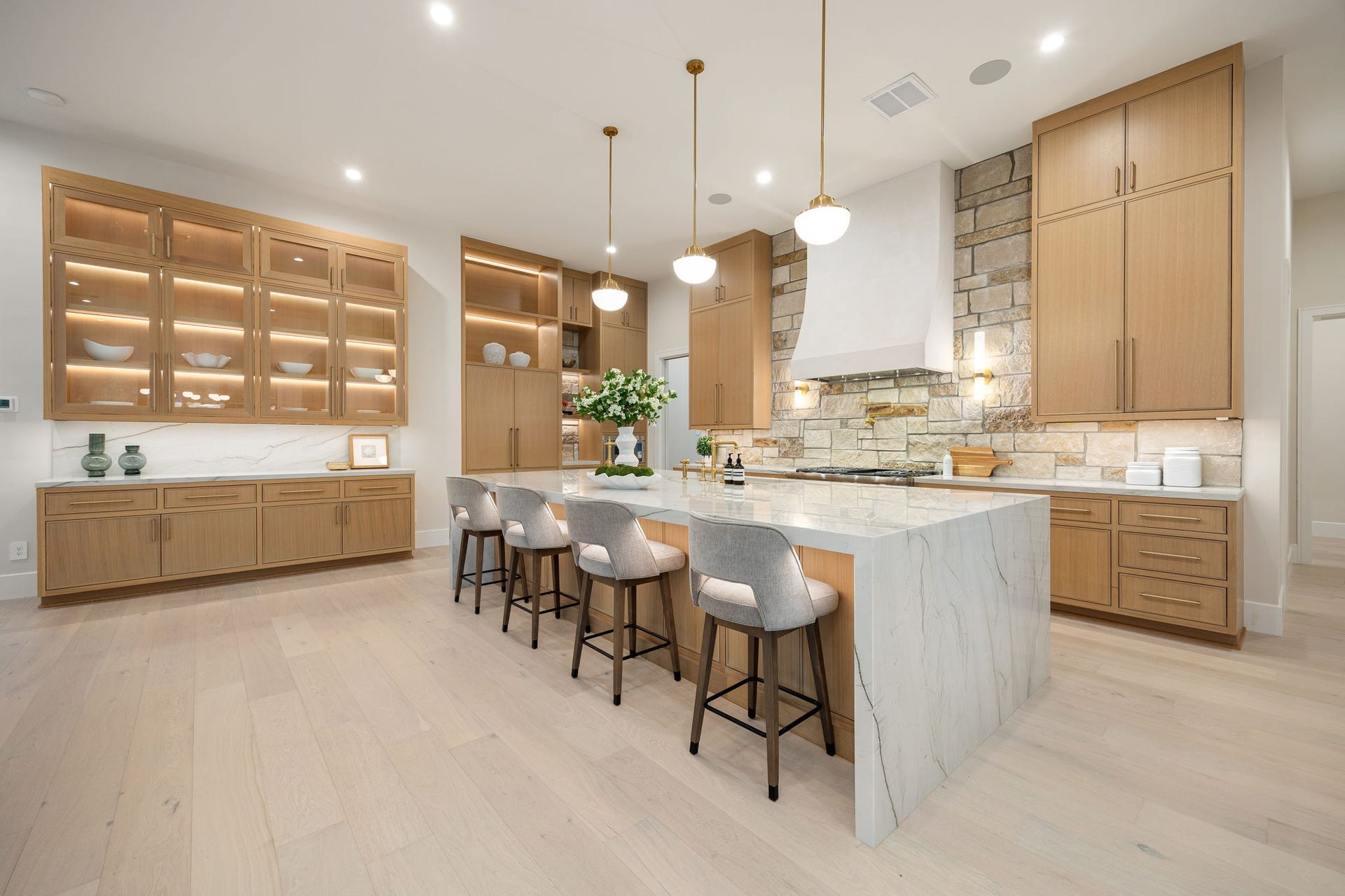 14106 Heatherfield Drive, Houston, TX 77079 This beautifully designed kitchen showcases refined craftsmanship with custom cabinetry, integrated lighting, and a spacious island perfect for gathering. Sleek pendant lighting adds warmth and balance, while the expansive layout enhances flow and functionality. The standout feature is the illuminated glass-front cabinetry, offering both display and ambiance, creating a sophisticated yet inviting atmosphere ideal for hosting or daily living.