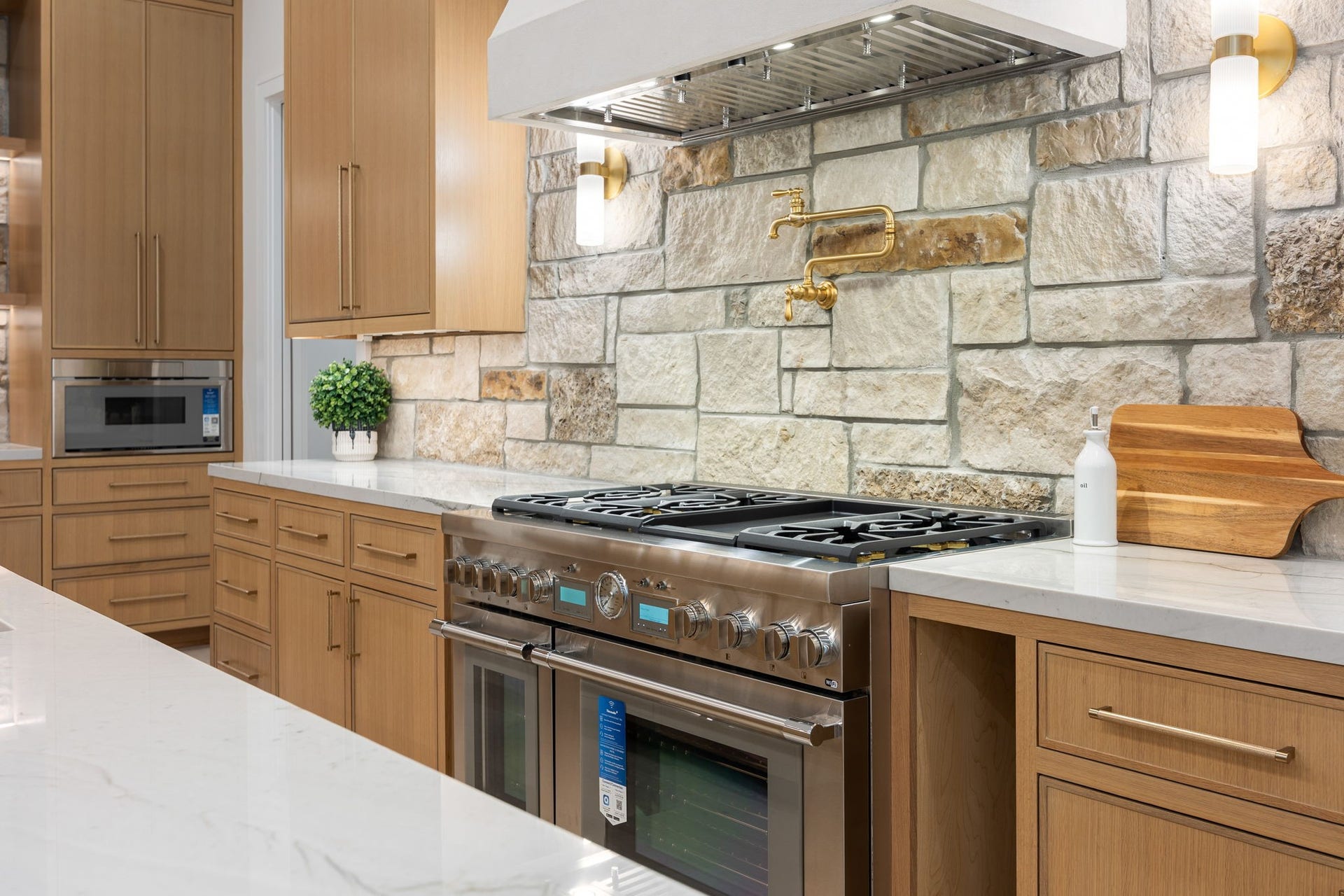 14106 Heatherfield Drive, Houston, TX 77079 A close-up perspective reveals a thoughtfully designed cooking space where texture and detail take center stage. The natural stone backsplash adds depth and character, paired with warm wood cabinetry for a timeless look. The highlight is the integrated pot filler, adding both convenience and elevated design, while the clean lines and layered materials create a polished and functional culinary environment.