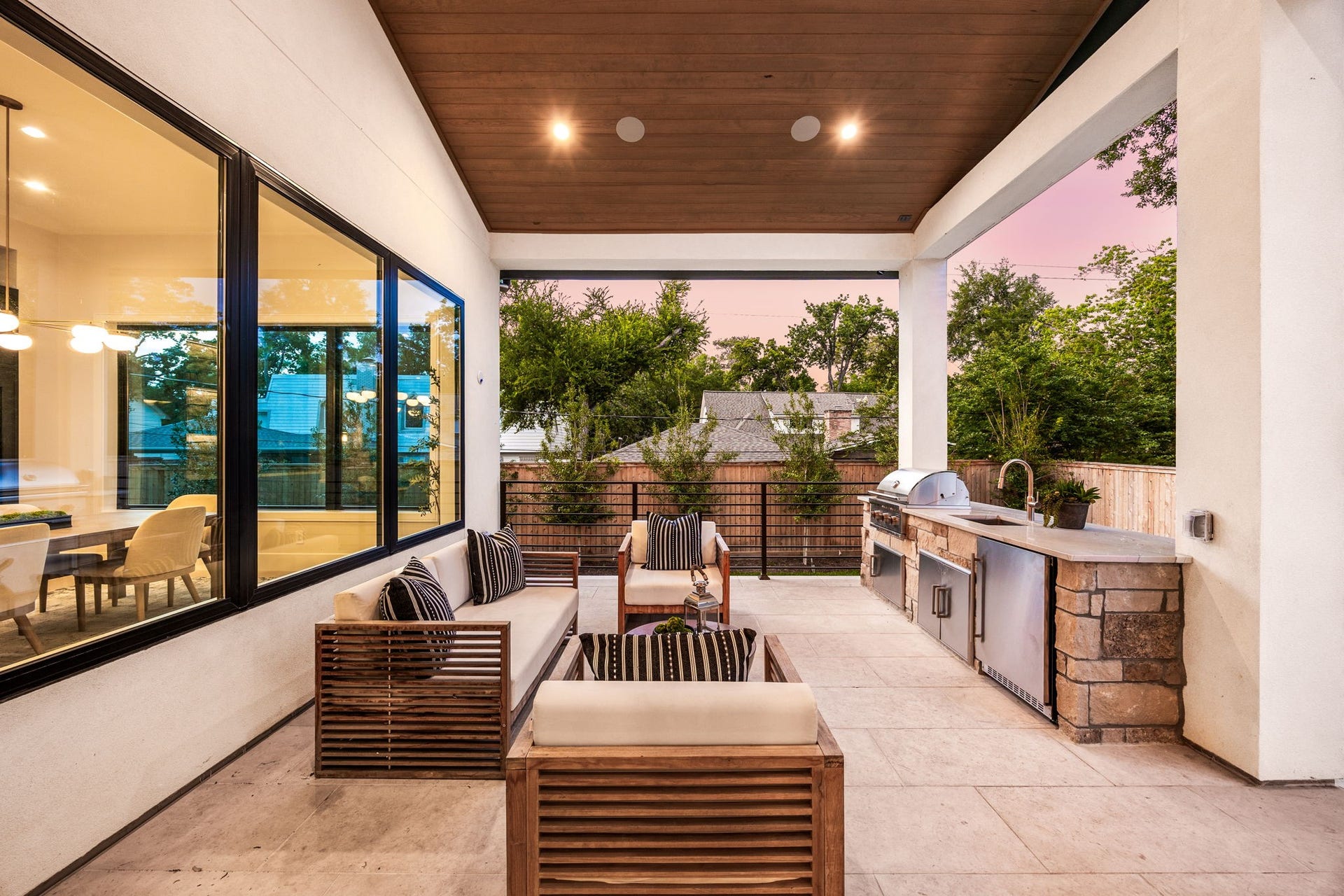 14106 Heatherfield Drive, Houston, TX 77079 This covered outdoor living space is designed for year-round enjoyment, blending comfort and style with a seamless indoor-outdoor connection. Cozy seating invites relaxation while overlooking the backyard. The highlight of this space is the fully equipped outdoor kitchen with built-in grill and prep area, making it perfect for entertaining and al fresco dining.