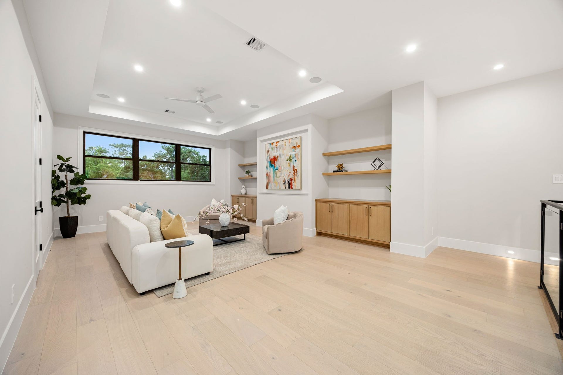 14106 Heatherfield Drive, Houston, TX 77079 A beautifully designed living space showcasing a seamless blend of comfort and style, with soft neutral tones and thoughtfully curated finishes. Built-in cabinetry and floating shelves provide both function and visual interest. The highlight of this room is the custom built-in wall with integrated storage and display shelving, creating a refined focal point perfect for showcasing art and dcor.