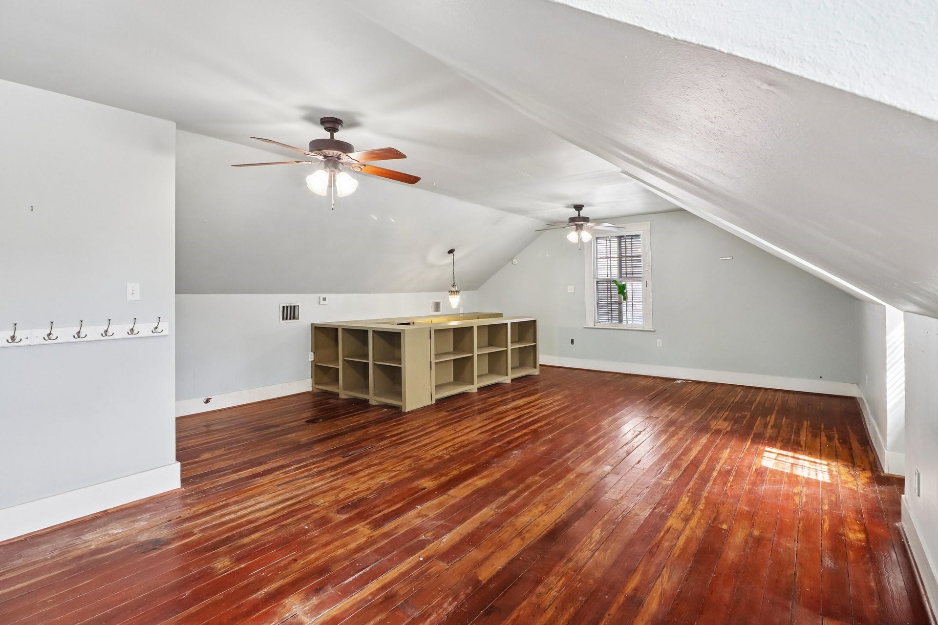 2318 Avenue M, Galveston, TX 77550 A bright upper-level room with wood flooring, a ceiling fan and windows beneath the sloped ceiling.