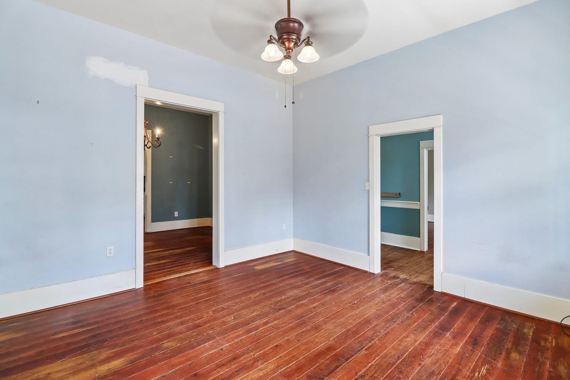 2318 Avenue M, Galveston, TX 77550 Wood flooring and a ceiling fan continue through this blue-painted room.