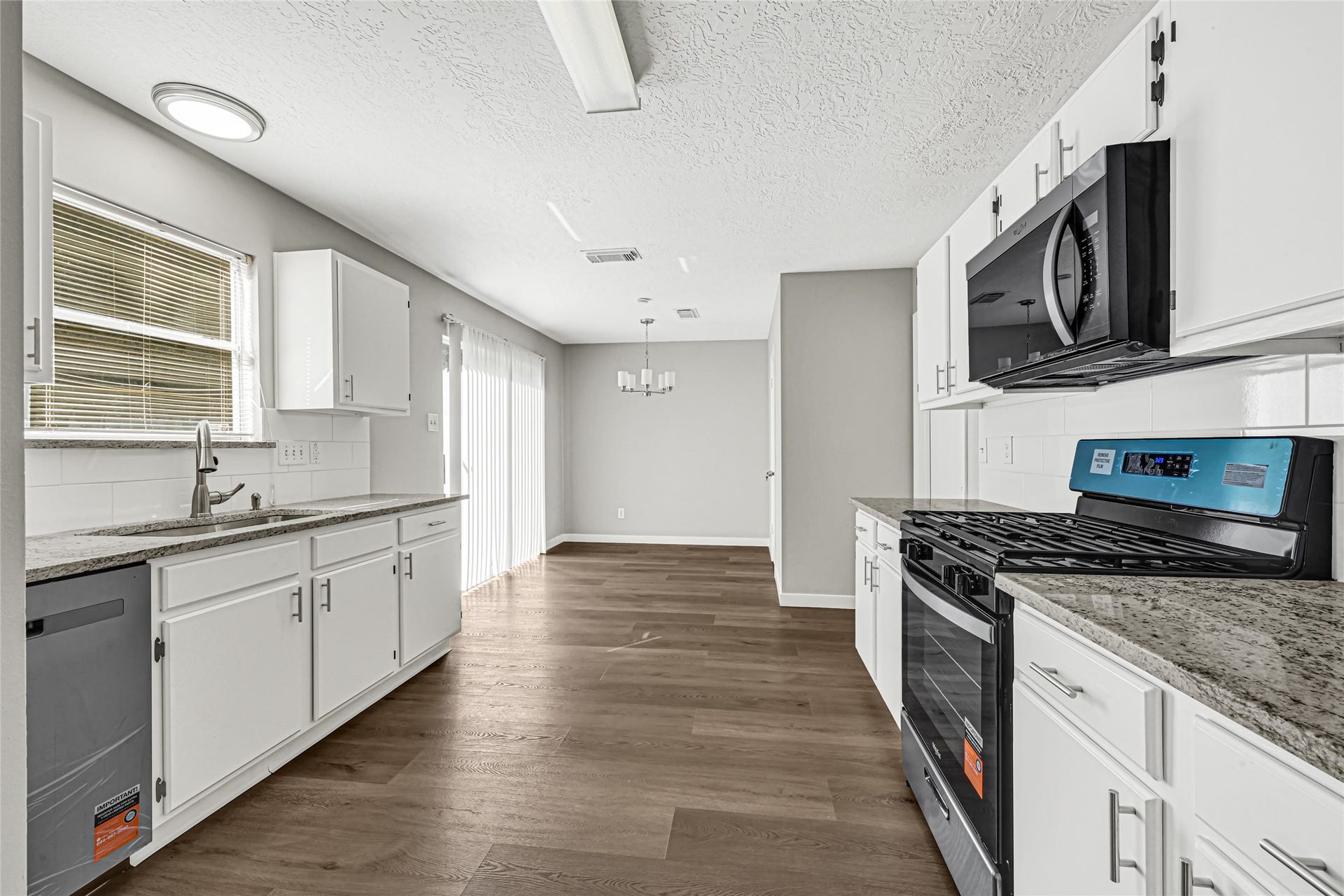 Updated kitchen featuring white cabinetry, granite countertops and stainless steel appliances