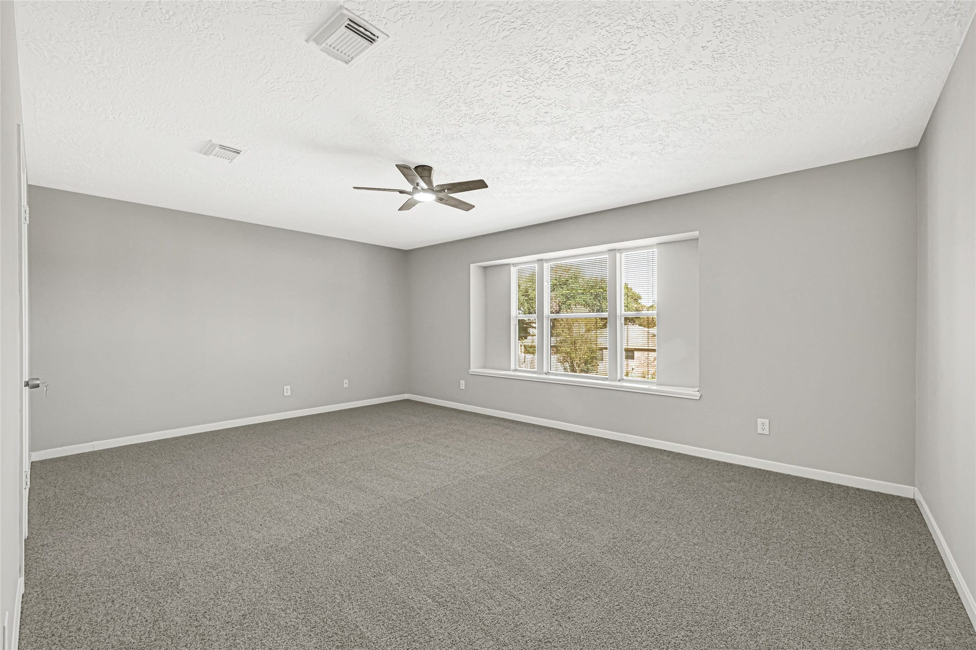 Generously sized primary bedroom with upgraded carpet and ceiling fan
