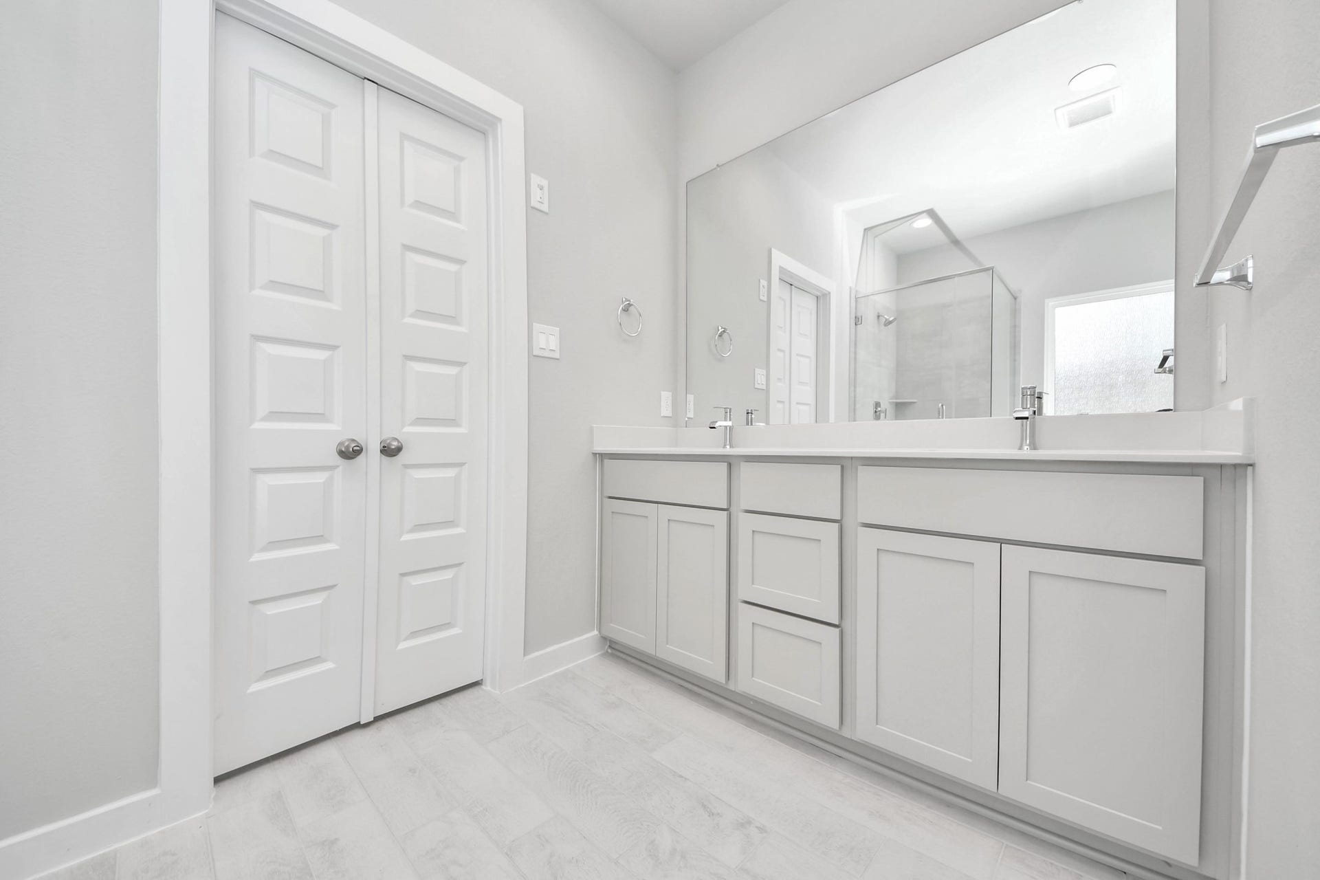 Elevate your daily routine at the elegant vanity, now equipped with double sinks, light countertops, modern hardware, and beautiful recessed lights. v