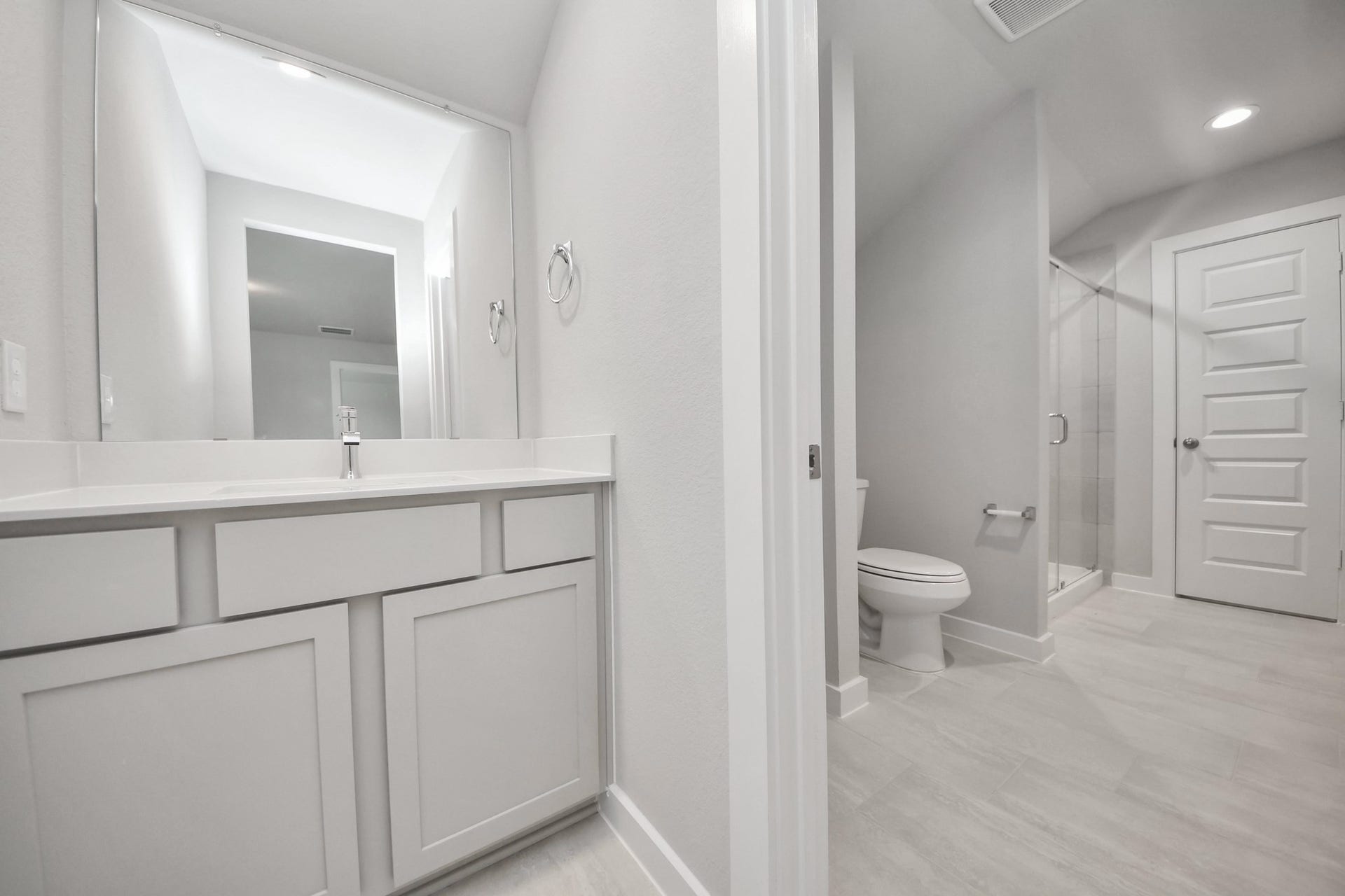 Experience convenience in the secondary bathroom, designed for Jack and Jill arrangements, now with a separate vanity area. This well-appointed space showcases stylish tile flooring, a bath/shower combo with an elegant tile surround, and light-stained wood cabinets. The beautiful light countertop adds a touch of sophistication, combining functionality and aesthetics seamlessly. Sample photo of completed home with similar floor plan. Actual colors and selections may vary.