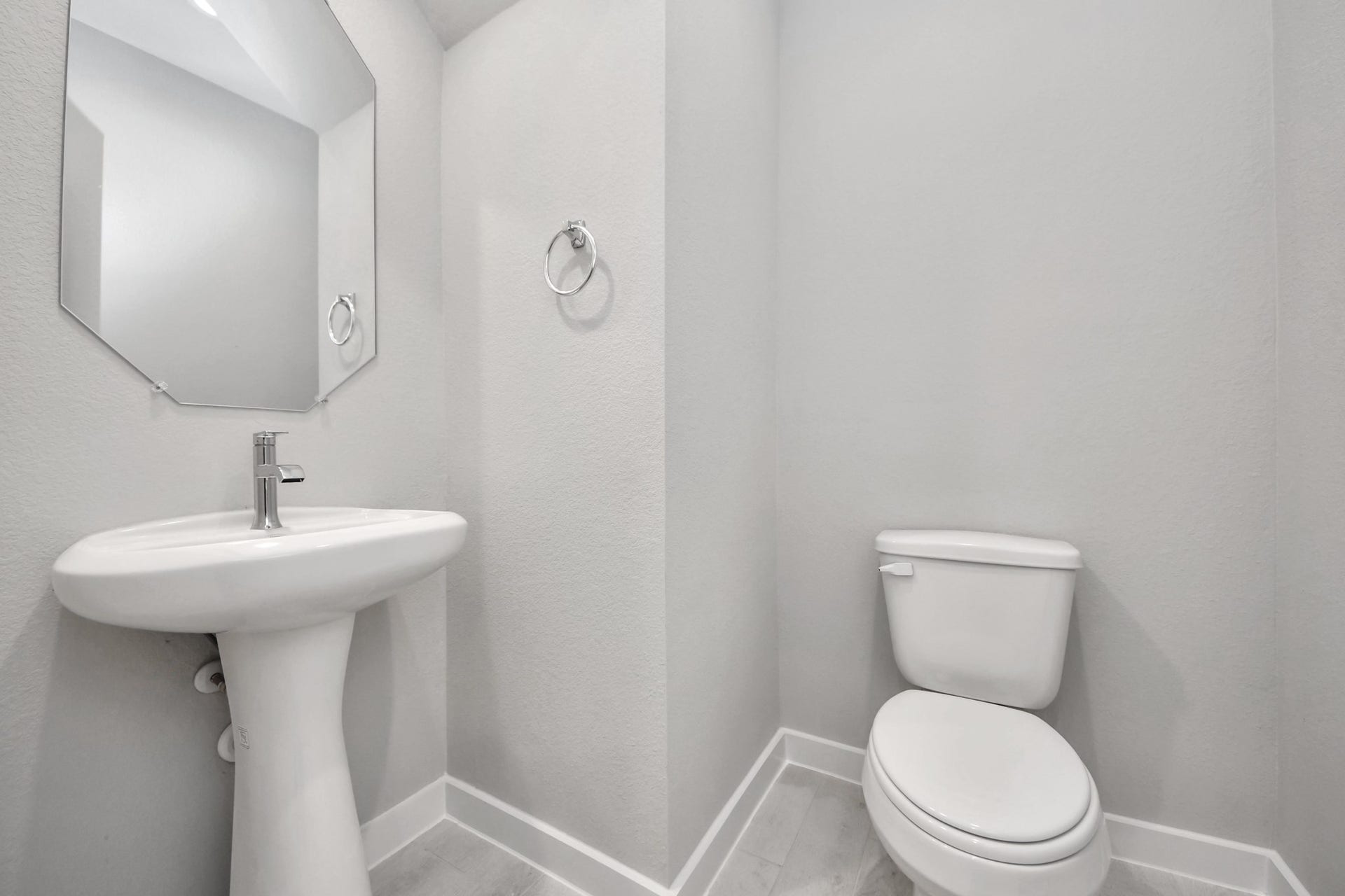 This half bathroom features a stylish pedestal sink, modern hardware, and bright recessed lighting, creating a sleek and inviting space. Sample photo of completed home with similar floor plan. Actual colors and selections may vary.