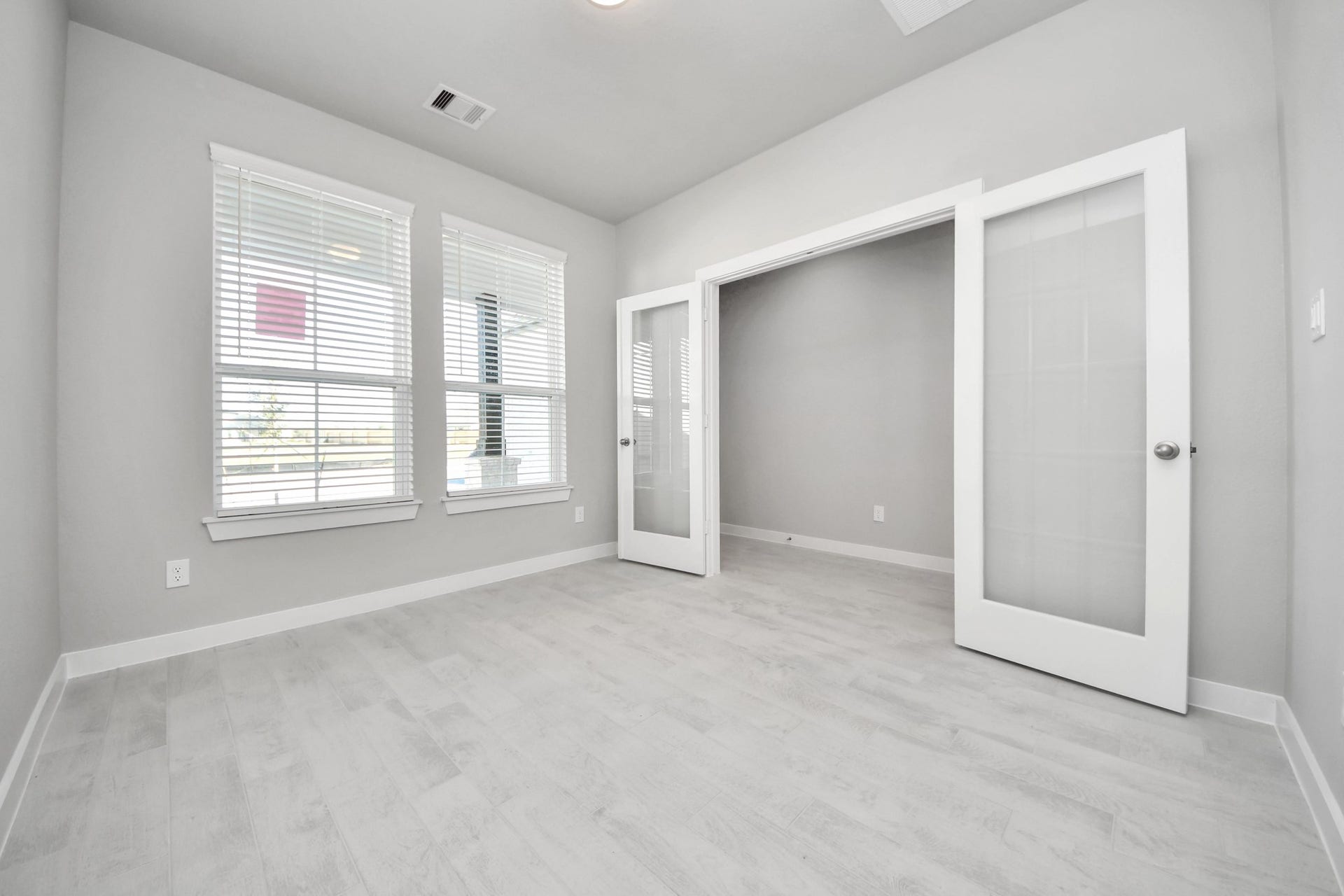 Experience the perfect blend of sophistication and warmth in this home office, boasting elegant wood-look tile flooring and flooded with natural light from expansive windows and French doors. Sample photo of completed home with similar floor plan. Actual colors and selections may vary.
