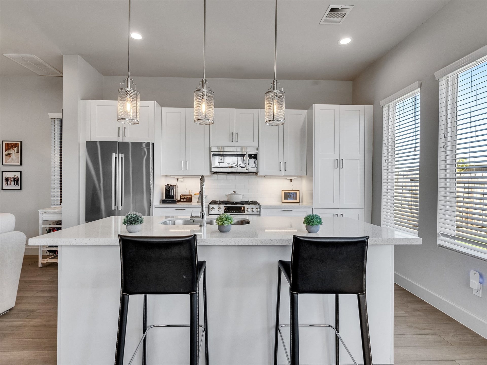 Stainless steel appliances, designer pendant lighting, and crisp white cabinetry.