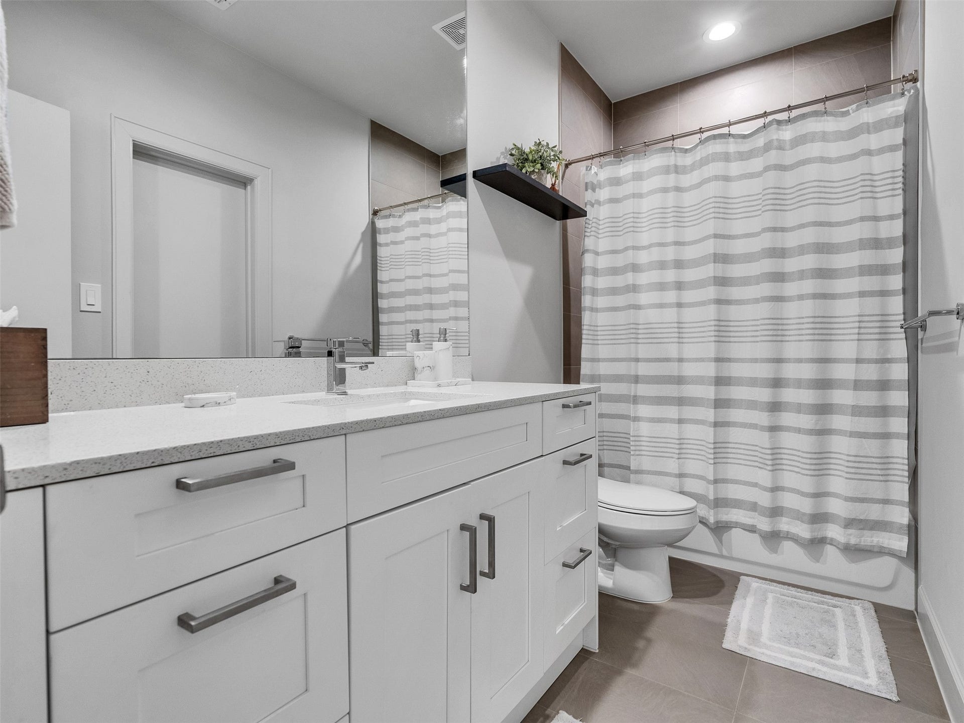 Modern guest bath featuring clean white cabinetry and designer tile.
