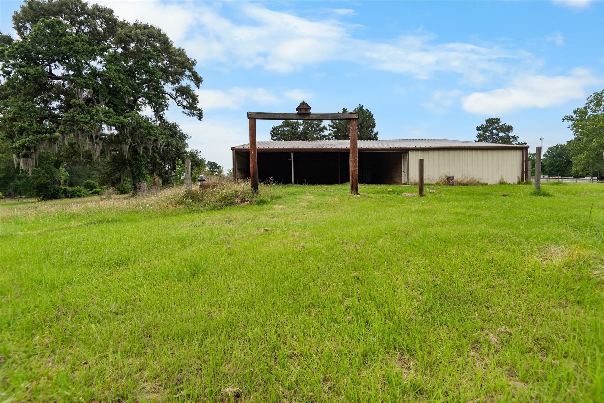 30307 Rickett Lane, Magnolia, TX 77355 Expansive pasture space with mature trees and a large barn ready for agricultural, recreational, or storage use.