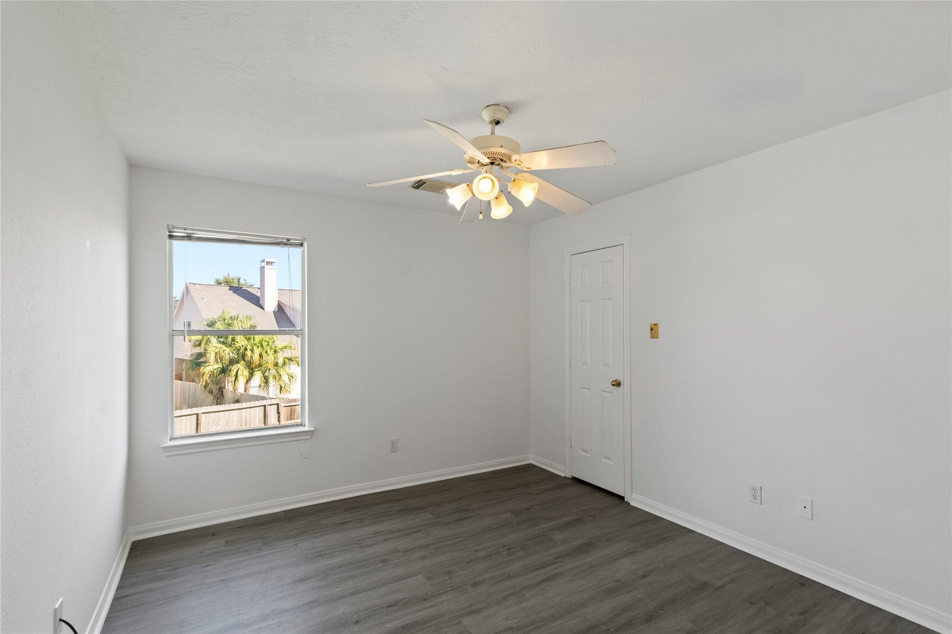 Bedroom 2 features modern gray flooring, a ceiling fan, and a window that fills the space with natural light.