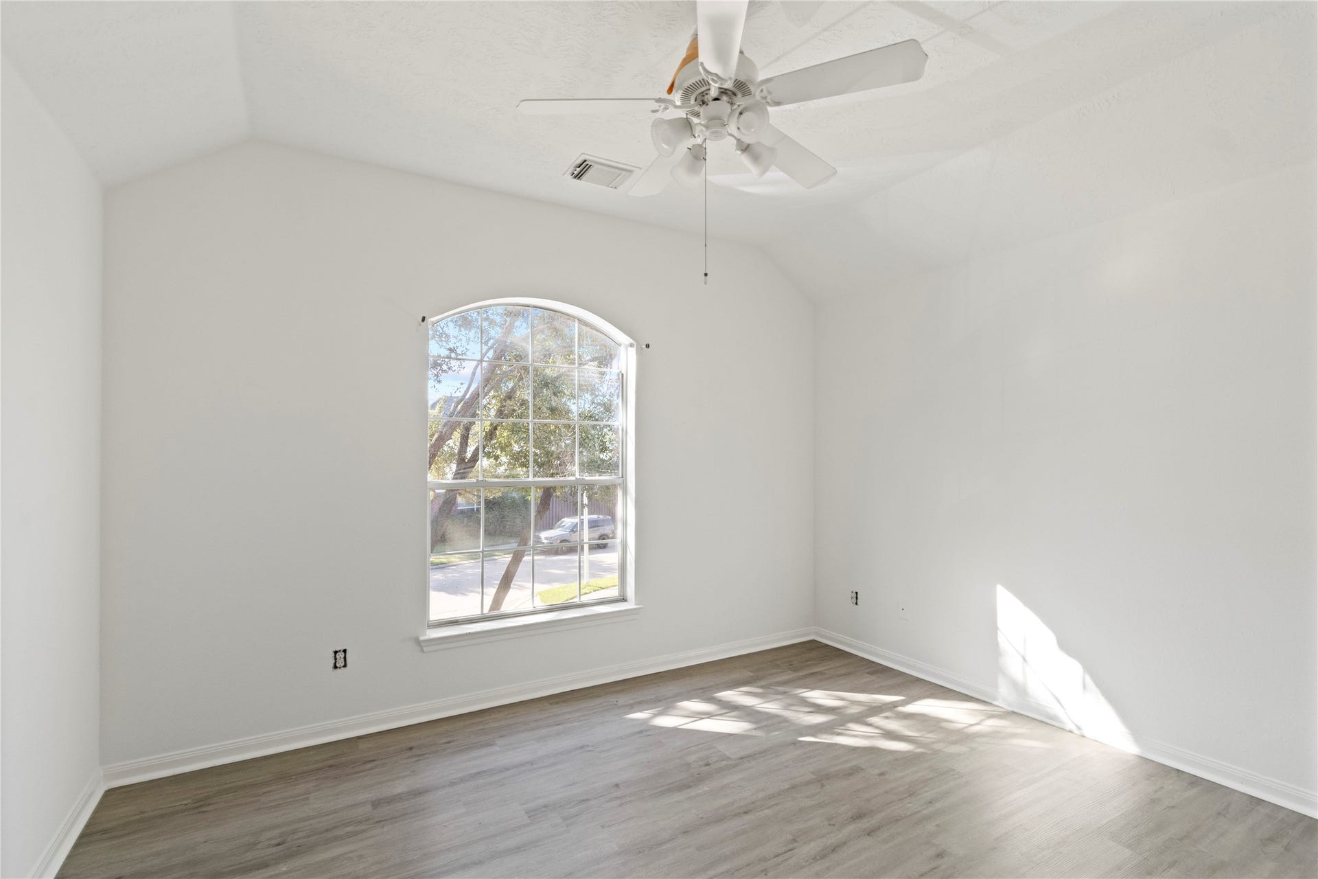 Bedroom 4 features vaulted ceilings, an elegant arched window, modern flooring, and abundant natural light, creating a bright and spacious retreat.