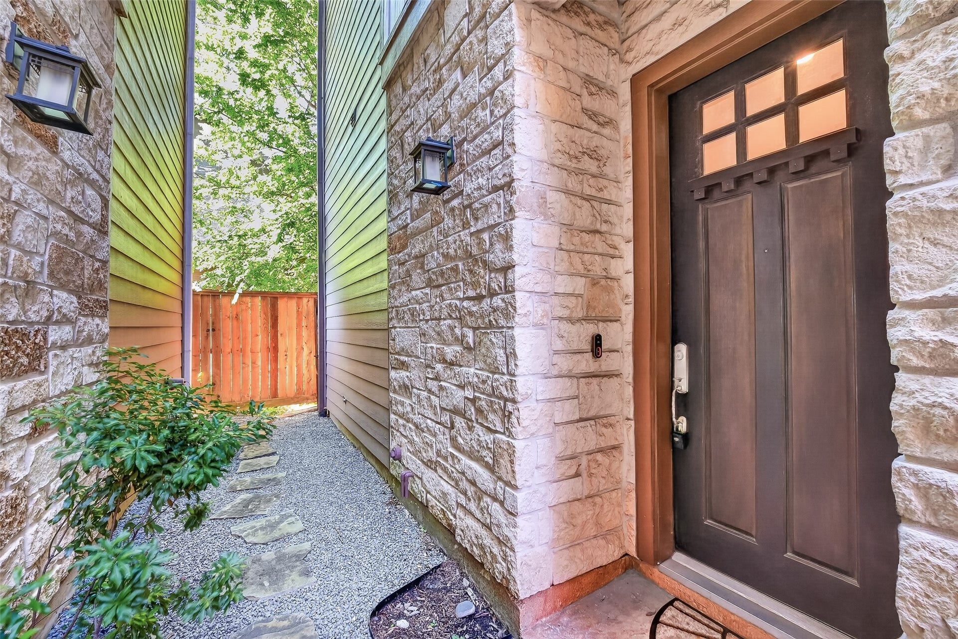 816 Yale Street, #C, Houston, TX 77007 Charming entrance with a solid wood door featuring decorative glass panes, set against a warm stone exterior. The pathway is landscaped with small shrubs, offering a welcoming approach to the home.