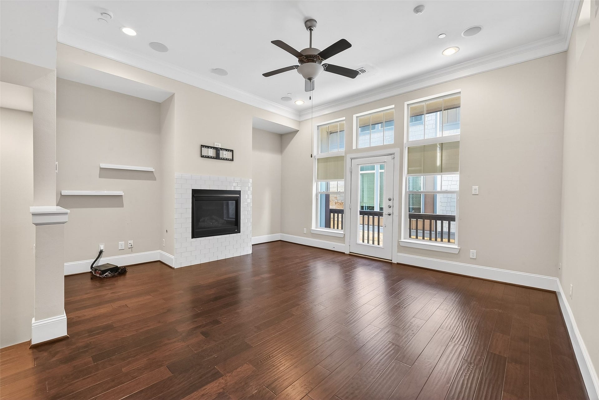 816 Yale Street, #C, Houston, TX 77007 This spacious living room features elegant hardwood floors, a modern fireplace, built-in shelving, and abundant natural light from large windows and a glass door leading to a balcony.