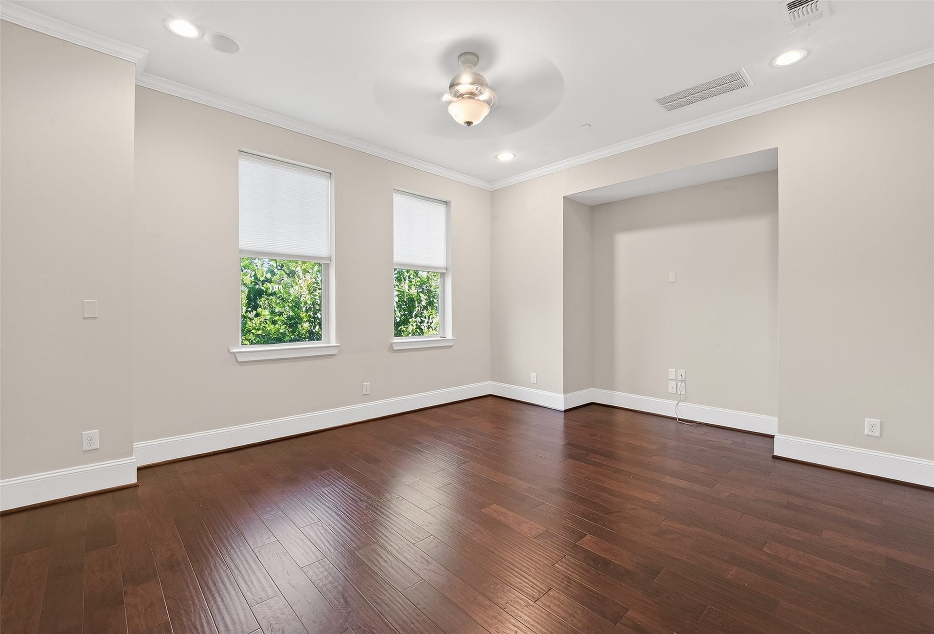 816 Yale Street, #C, Houston, TX 77007 This primary bedroom features hardwood floors, neutral walls, and recessed lighting. It has two large windows with blinds, offering natural light and a pleasant view. The ceiling fan adds comfort, and an alcove provides extra space for customization.