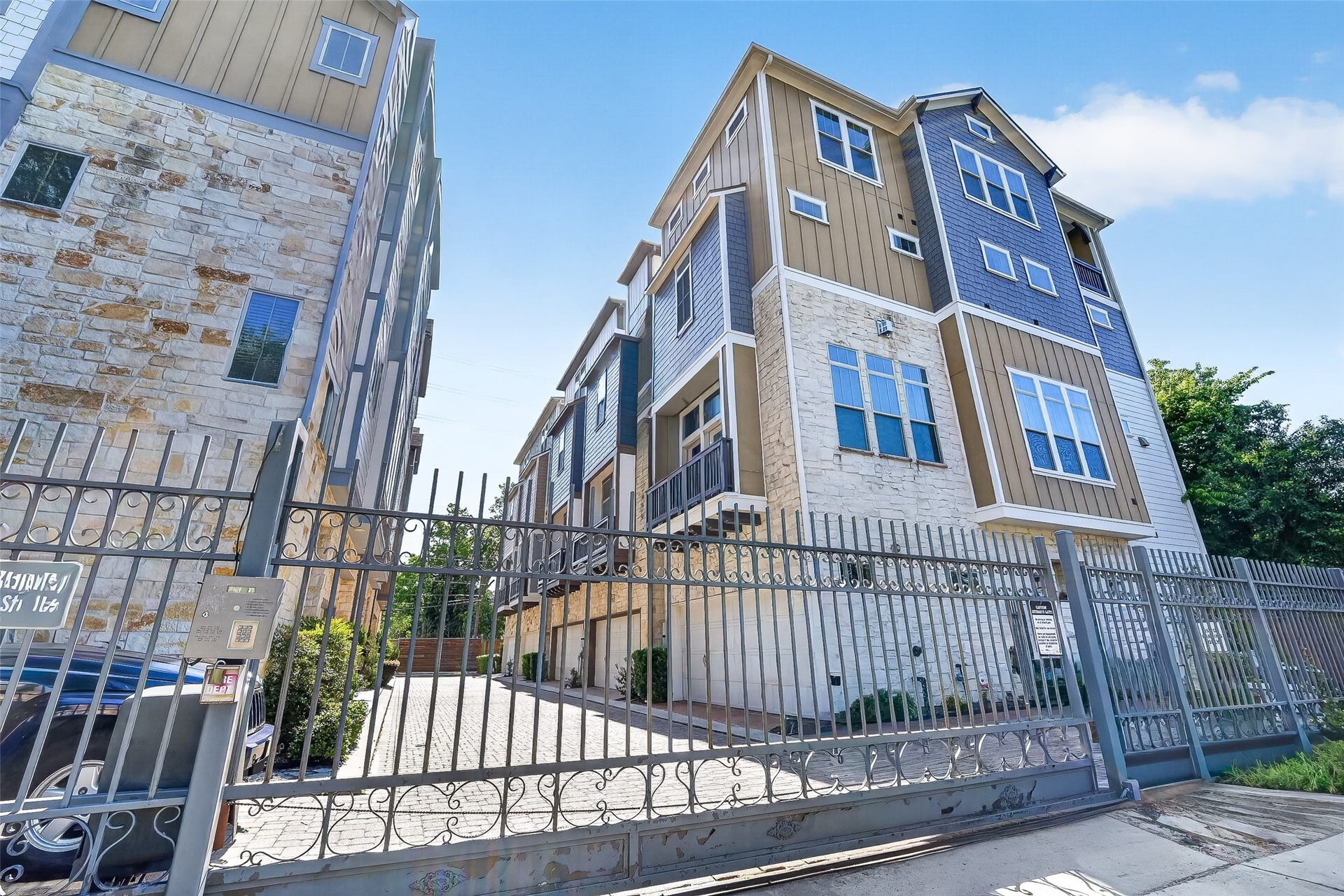 816 Yale Street, #C, Houston, TX 77007 Modern multi-story townhouse with a mix of stone and siding exterior. It features large windows, a gated entry for added security, and a driveway leading to the residences. Ideal for urban living with a stylish design.