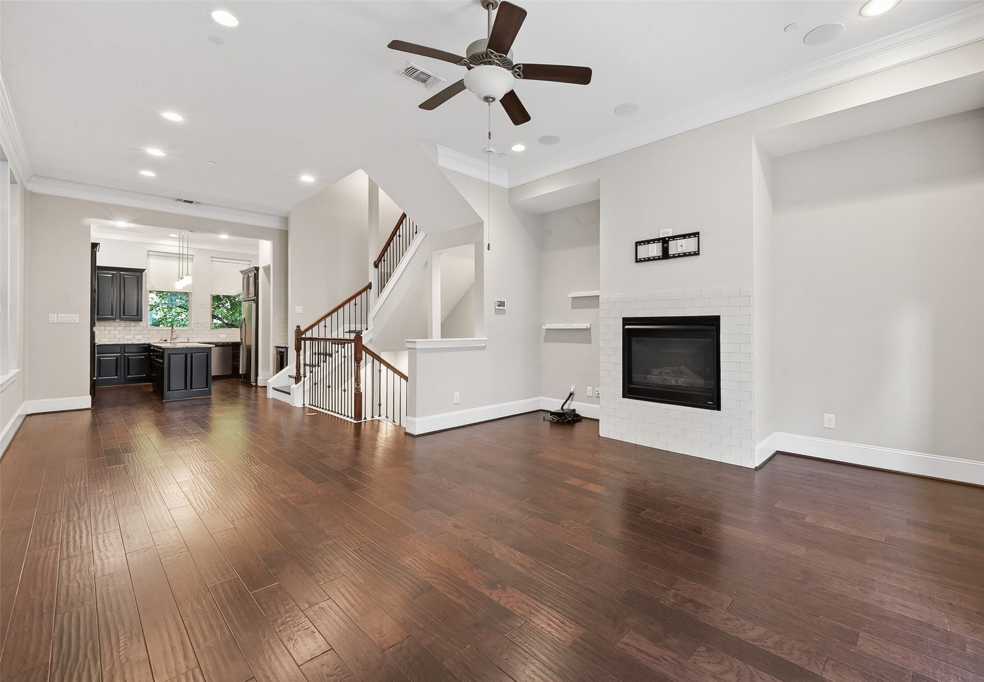 816 Yale Street, #C, Houston, TX 77007 This spacious living area features hardwood floors, a modern ceiling fan, and a cozy fireplace. Ample natural light comes through large windows, and a staircase provides access to upper levels.