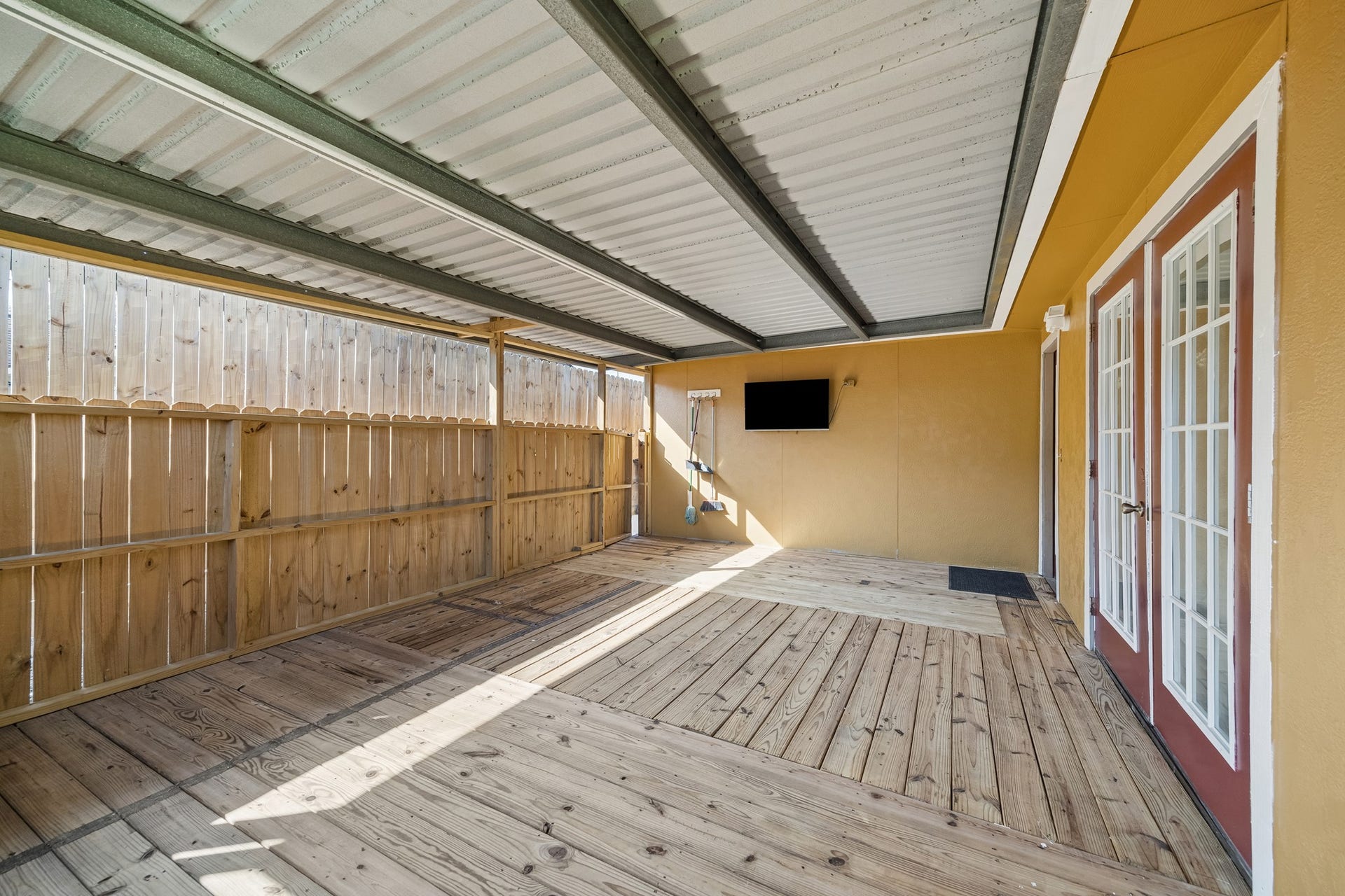 10702 Duncum Street, Houston, TX 77013 Spacious covered patio with wooden decking and French doors, perfect for outdoor relaxation and entertainment.