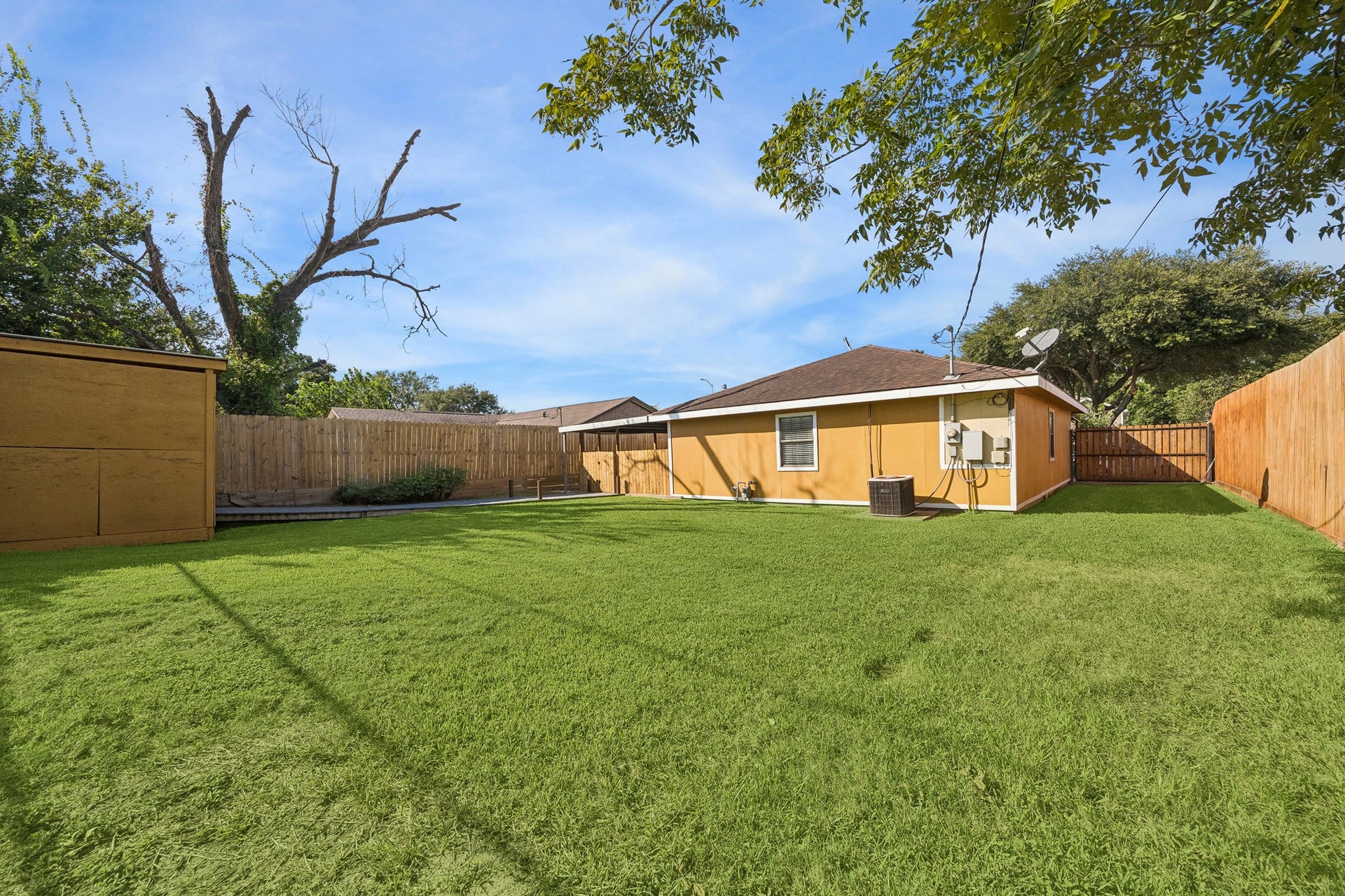 10702 Duncum Street, Houston, TX 77013 Expansive backyard with lush green lawn, privacy fencing, and mature trees, perfect for outdoor activities and relaxation.