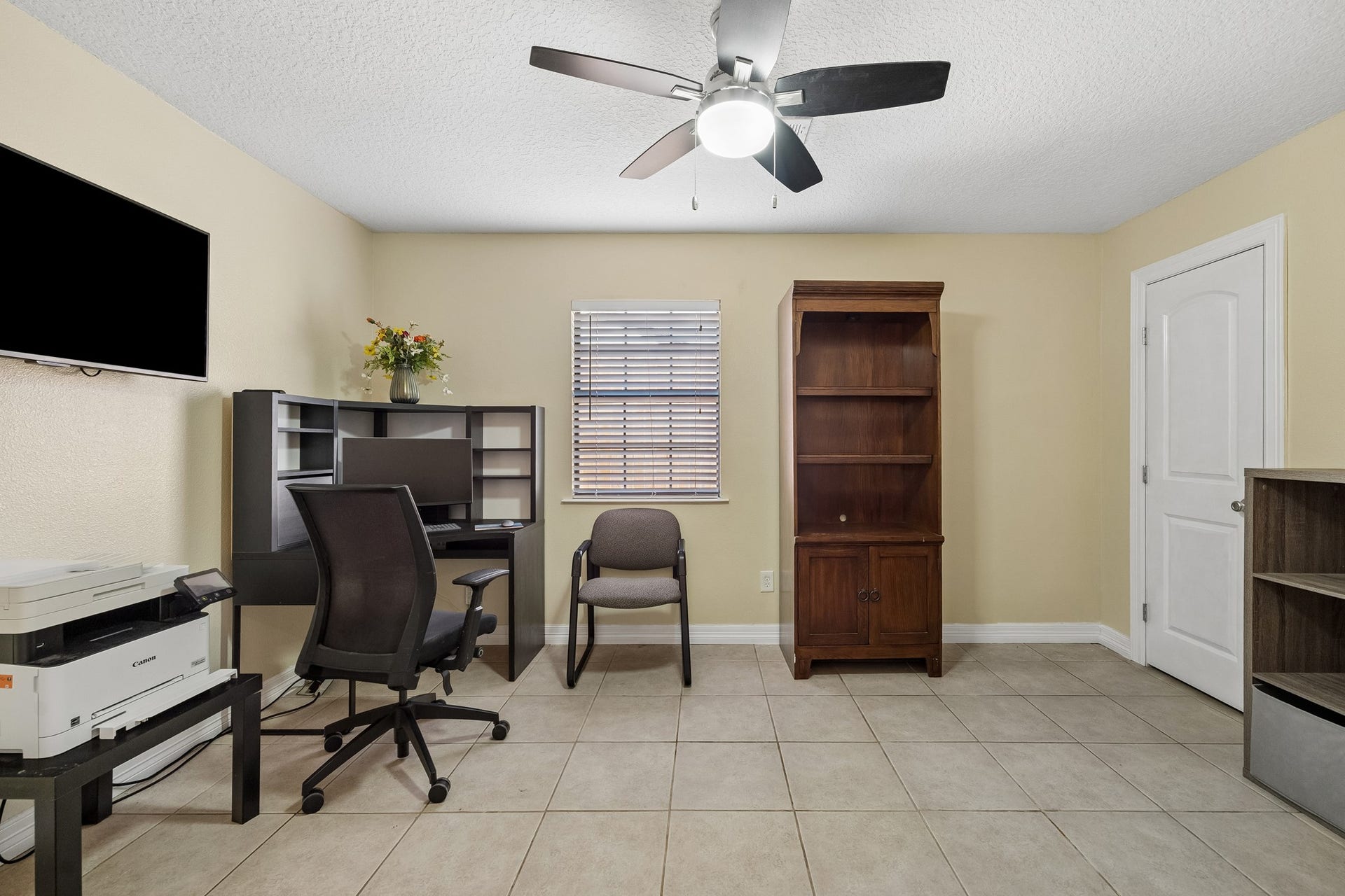 10702 Duncum Street, Houston, TX 77013 Bright and functional home office with neutral walls, tiled flooring, and ample storage space, featuring a ceiling fan for comfort.