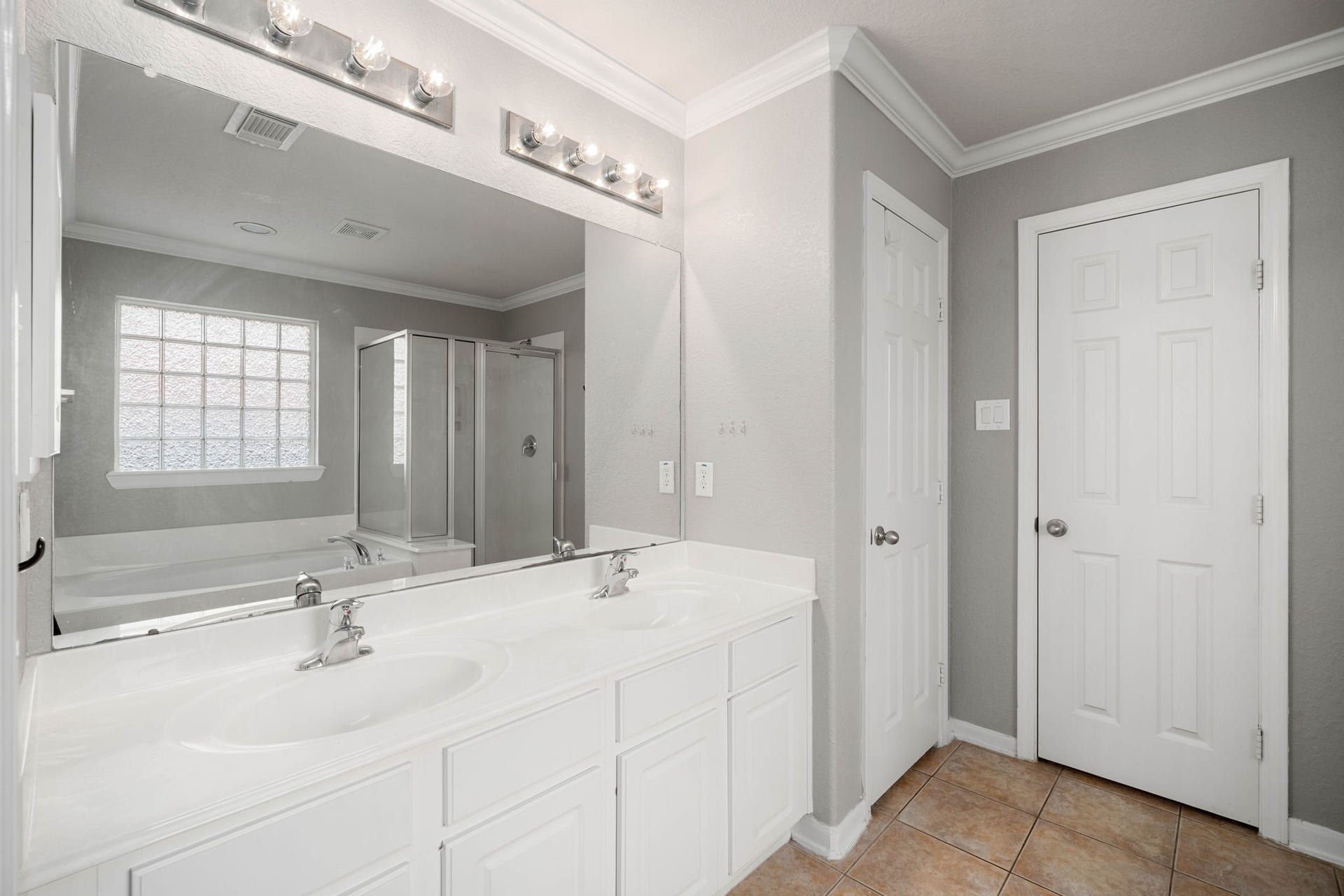 10422 Antelope Alley, Missouri City, TX 77459 The well-appointed ensuite primary bath features double sinks and an expansive mirror. Bright lighting and modern finishes create a functional and refreshed atmosphere for your daily routine.