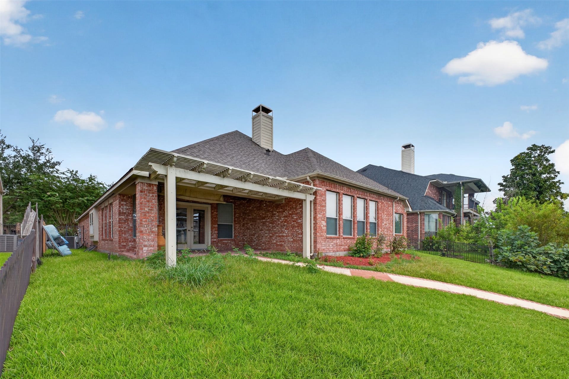 14326 Manorbier Lane, Sugar Land, TX 77498 This photo showcases a charming waterfront home with a spacious backyard, a well-maintained lawn, and a private dock. The house features a covered patio, surrounded by lush greenery, perfect for outdoor relaxation and enjoying serene water views.