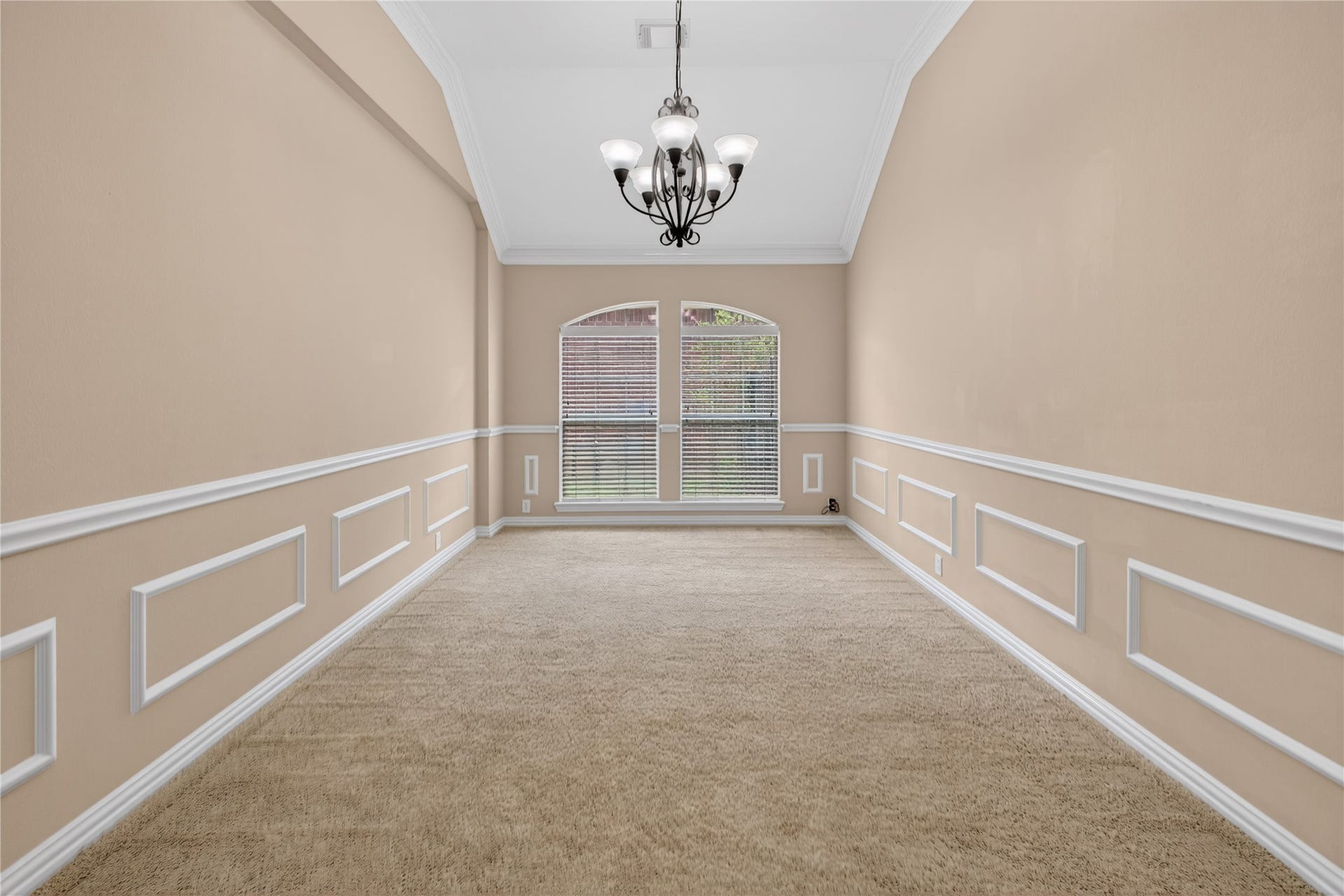 14326 Manorbier Lane, Sugar Land, TX 77498 This room features elegant wainscoting and a neutral color palette, with a large window providing natural light. A stylish chandelier adds sophistication, and the carpeted floor offers warmth, making it ideal for a dining or formal living space.