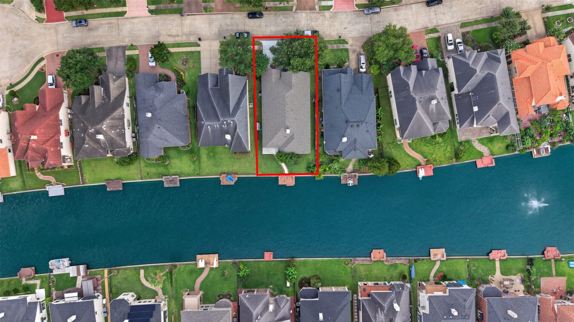 14326 Manorbier Lane, Sugar Land, TX 77498 This aerial view shows a waterfront property highlighted in red. The house is part of a row of homes with direct access to a canal, featuring tidy yards and driveways. Ideal for buyers seeking a scenic, waterside living environment.