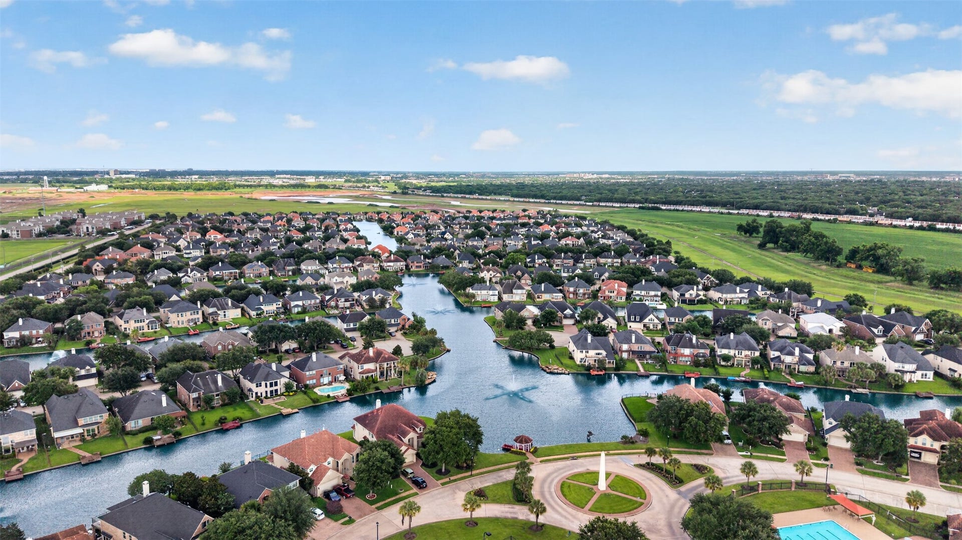 14326 Manorbier Lane, Sugar Land, TX 77498 This aerial photo showcases a serene residential neighborhood with homes lining a picturesque canal, offering waterfront views. The area features lush greenery, spacious properties, and is complemented by a community pool, creating an inviting suburban environment.