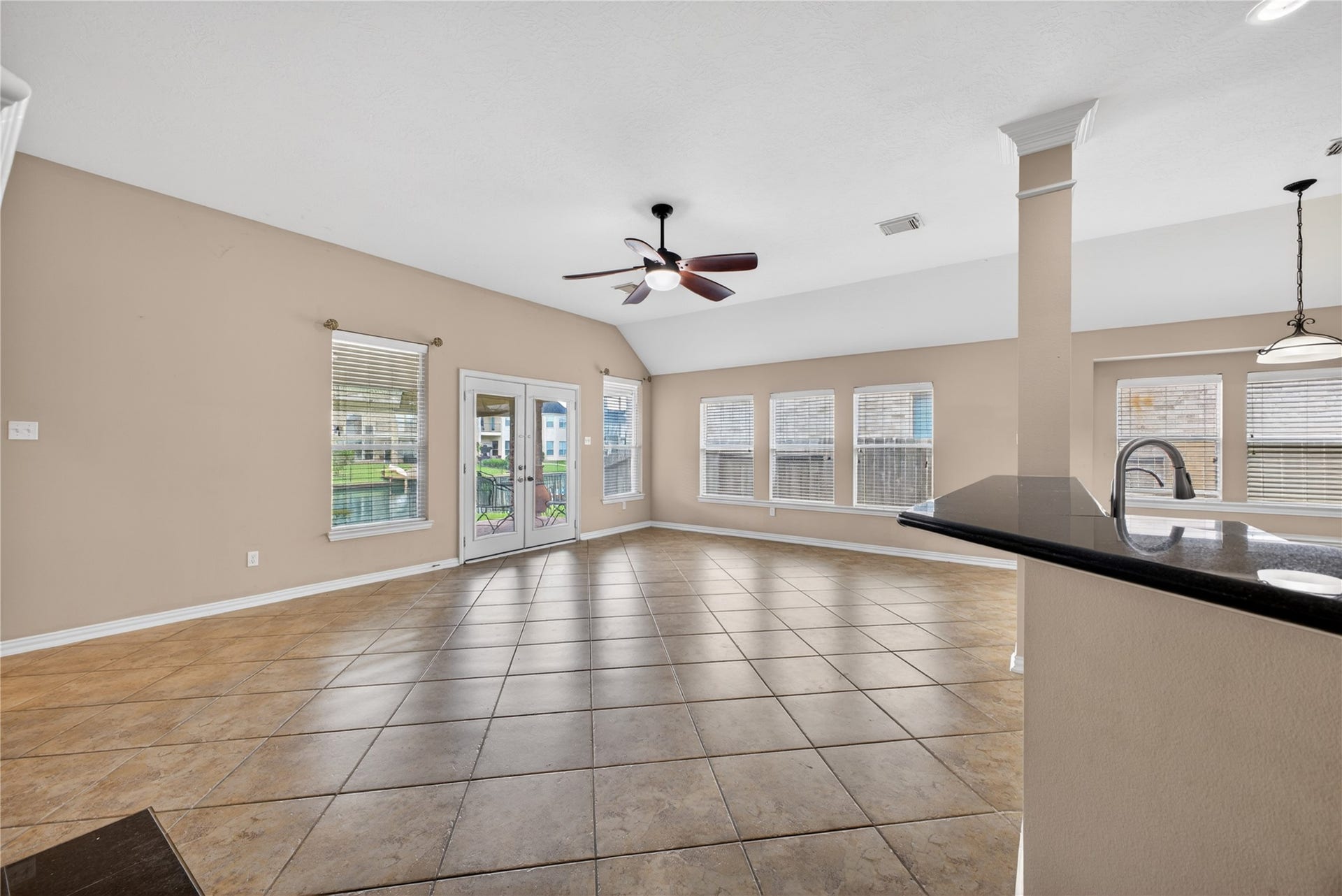 14326 Manorbier Lane, Sugar Land, TX 77498 This spacious living area features large windows for ample natural light, tile flooring, a ceiling fan, and an open layout that connects to the kitchen with a stylish countertop. The room offers patio doors leading to an outdoor space, perfect for entertaining.