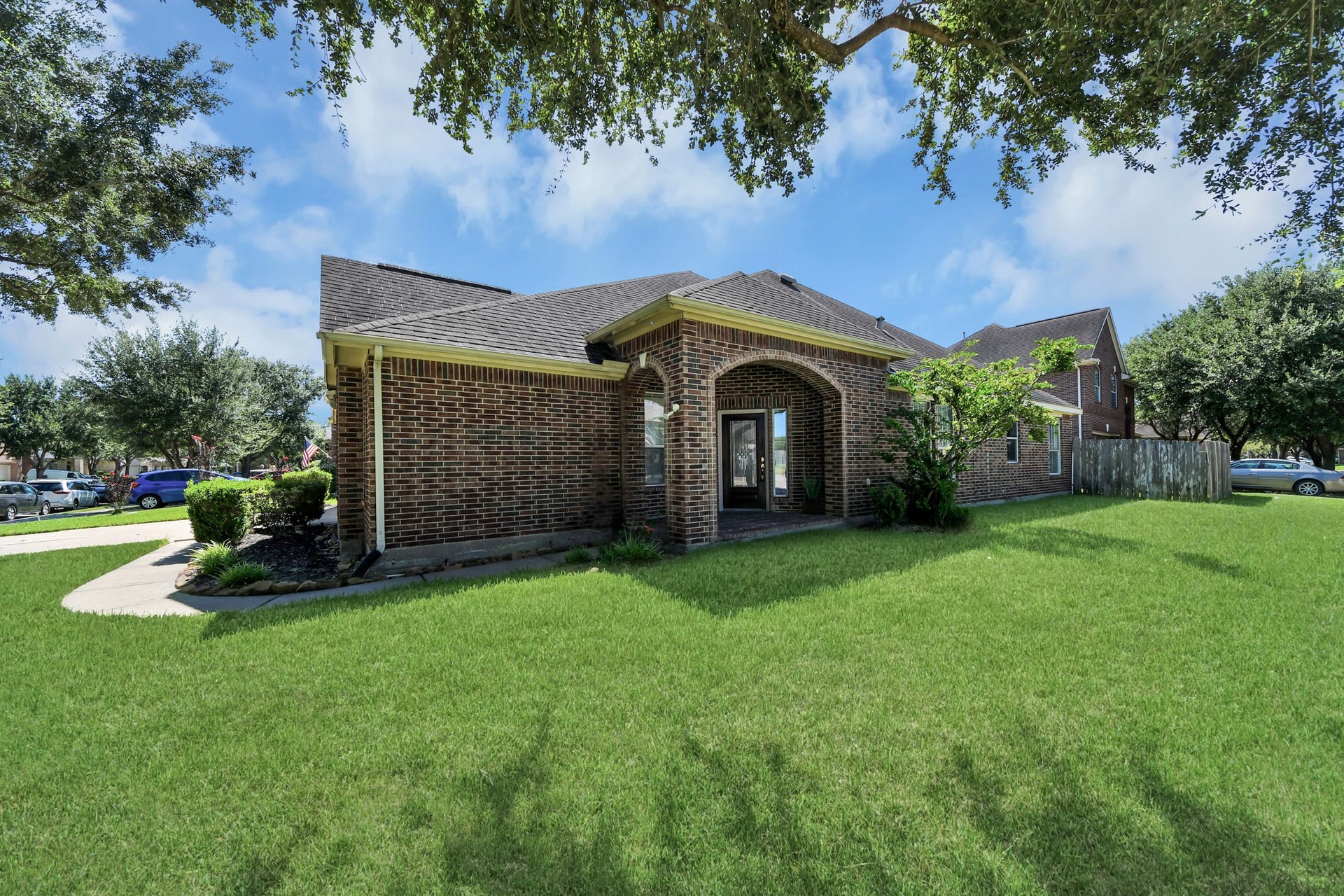 13935 Charterhouse Way, Sugar Land, TX 77498 Charming brick home with a spacious front yard, mature trees, and a two-car garage, offering a warm and inviting curb appeal.