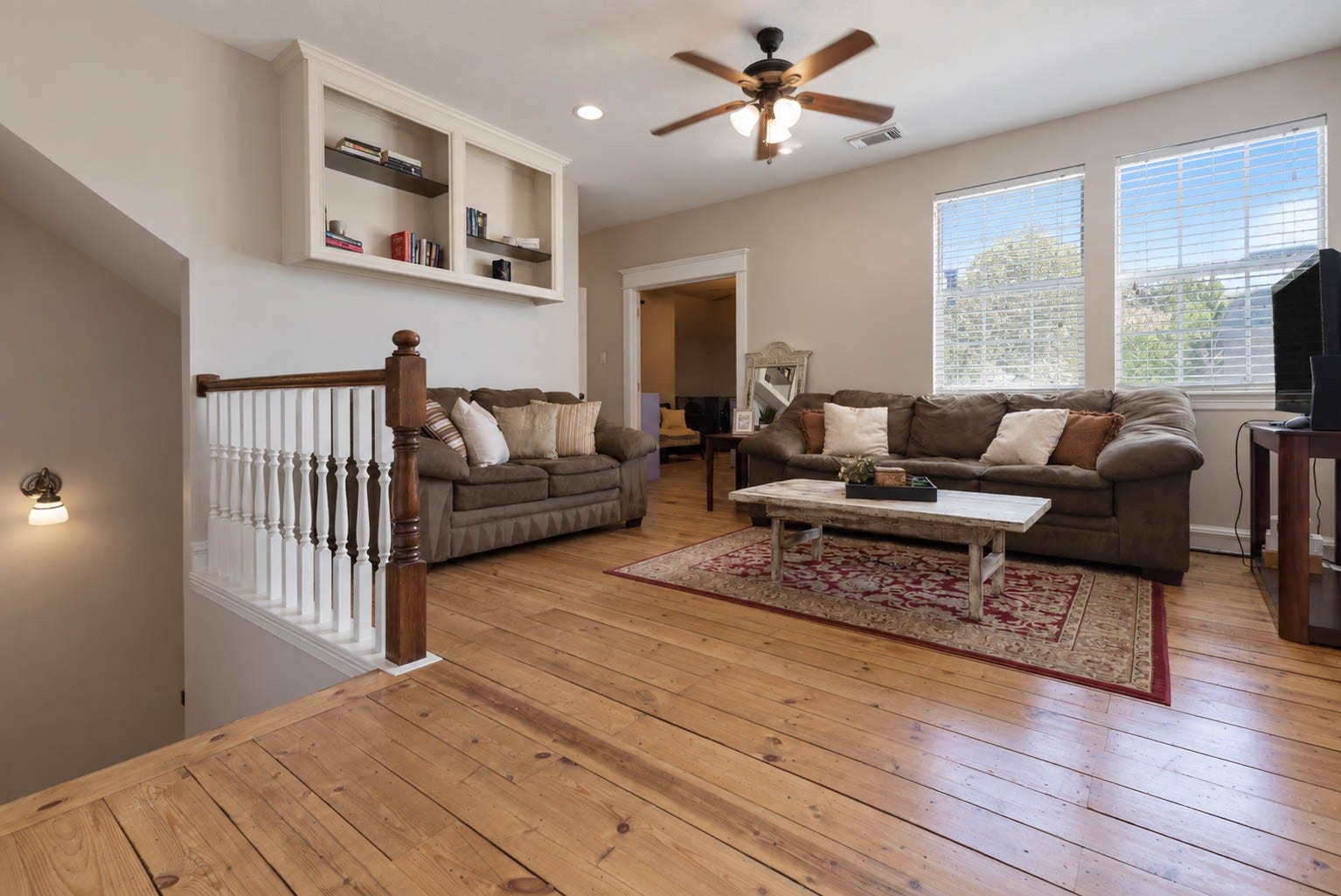 33103 Whickham Circle, Fulshear, TX 77441 The second-level living area offers a welcoming gathering space with hardwood flooring, built-in shelving, recessed lighting, & a ceiling fan. Large windows fill the room with natural light, enhancing its spacious and inviting feel.