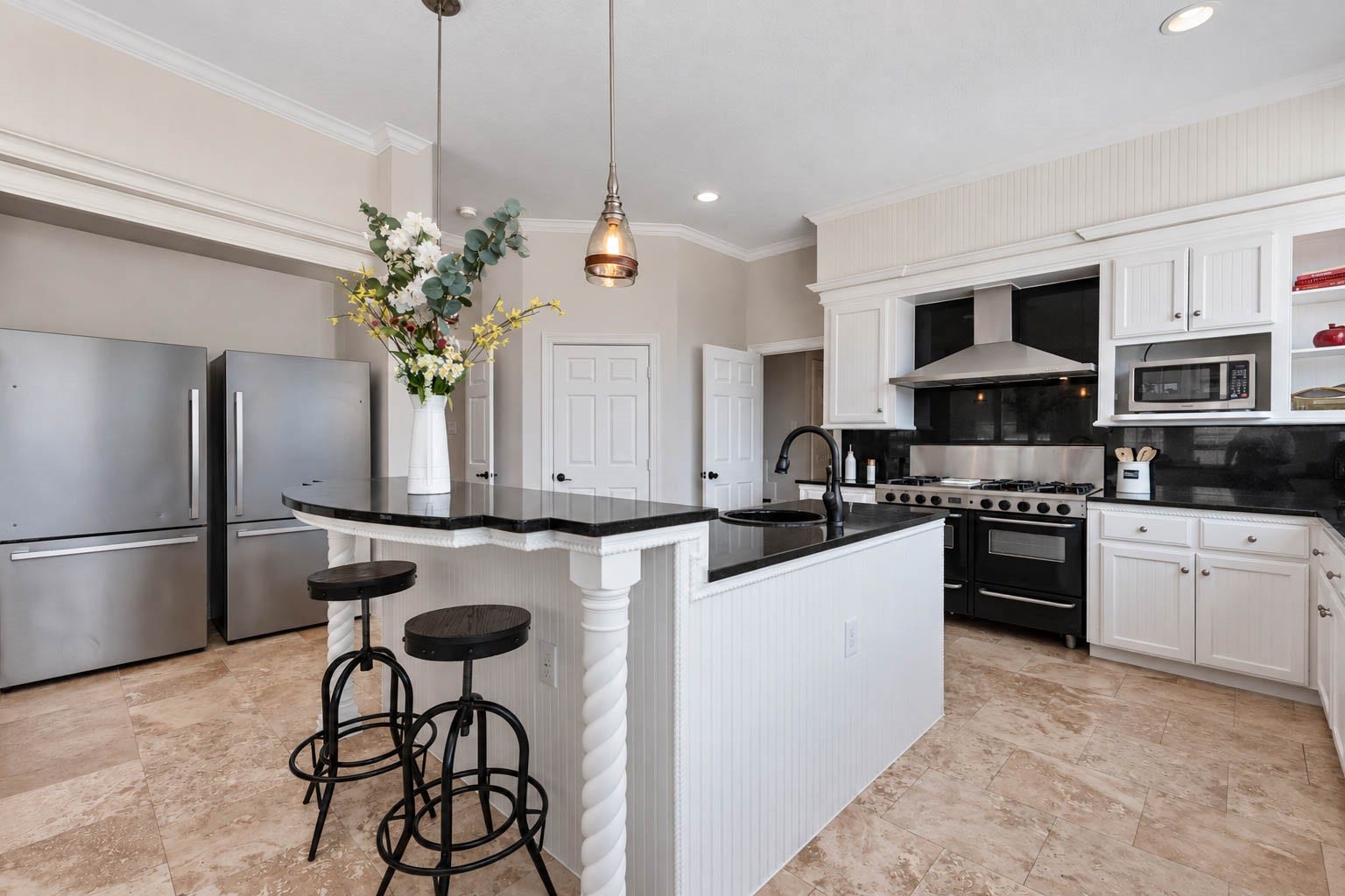 33103 Whickham Circle, Fulshear, TX 77441 Another angle showcases the kitchens impressive culinary design with a professional-style gas range, double ovens, & substantial stainless vent hood. Multiple work surfaces, a spacious breakfast bar, & walk-in pantry add exceptional functionality.