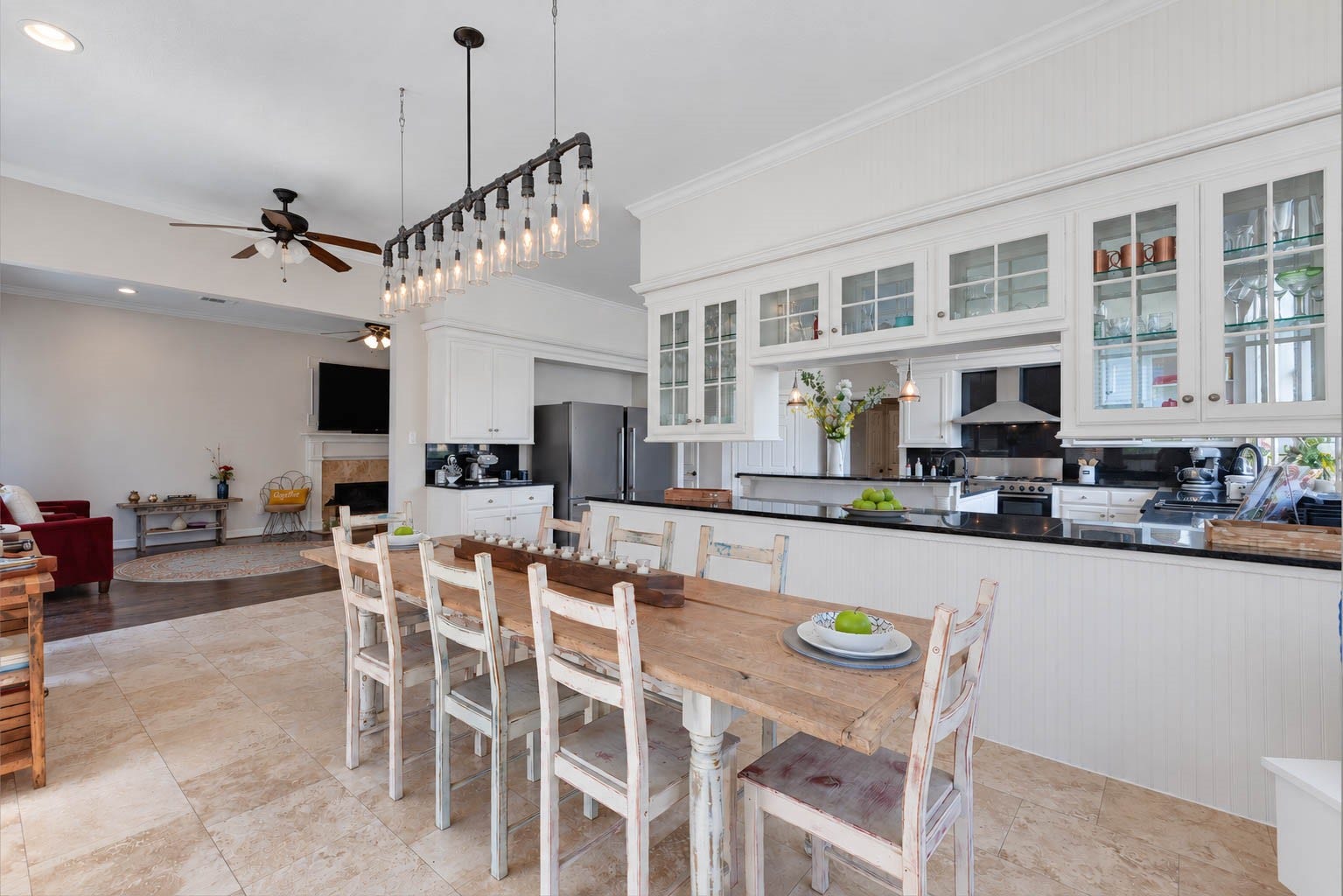33103 Whickham Circle, Fulshear, TX 77441 A striking linear chandelier beautifully defines the breakfast area, while glass-front cabinetry and rich contrasting countertops create a sophisticated backdrop. Open sightlines enhance the sense of space and provide a seamless connection to kitchen and family room.