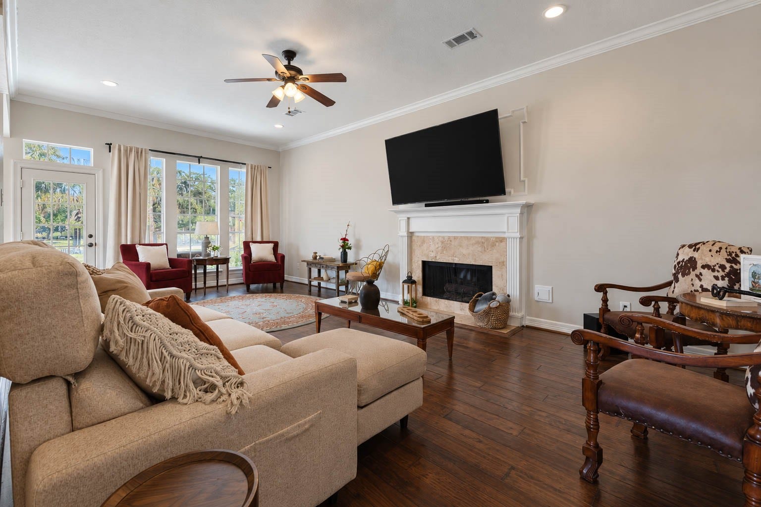 33103 Whickham Circle, Fulshear, TX 77441 The generously sized family room exudes warmth and elegance with rich hardwood flooring, crown molding, recessed lighting, a ceiling fan, & a gas-log fireplace. Expansive windows and a glass-paneled door fill the space with natural light while offering seamless access to the screened porch and backyard retreat.